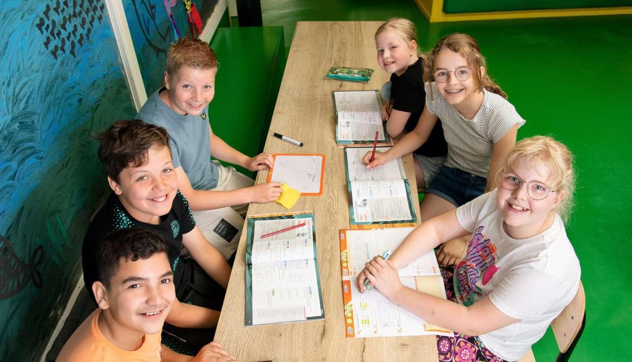 Kindcentrum De Spreng in Barneveld: Een groep blije kinderen aan een tafel met schoolboeken. Kindcentrum De Spreng in Barneveld: Een groep blije kinderen aan een tafel met schoolboeken.