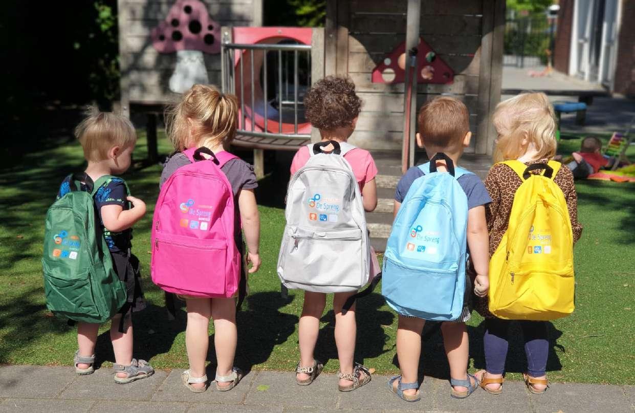 Kindcentrum De Spreng in Barneveld toont blije kinderen met kleurrijke rugzakken op het schoolplein. Kindcentrum De Spreng in Barneveld toont blije kinderen met kleurrijke rugzakken op het schoolplein.