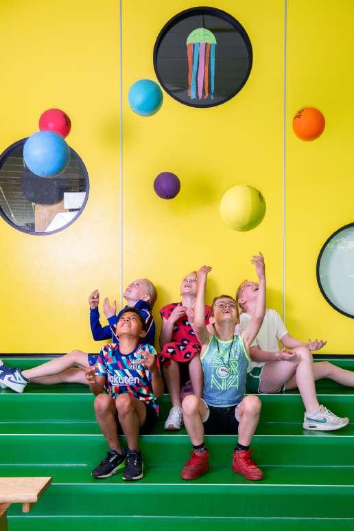 Kindcentrum De Spreng in Barneveld, waar kinderen enthousiast met ballen spelen op de groene trappen. Kindcentrum De Spreng in Barneveld, waar kinderen enthousiast met ballen spelen op de groene trappen.