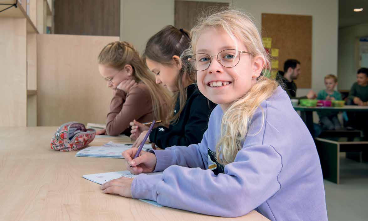 Kindcentrum De Spreng in Hoevelaken: Een blije leerling aan een tafel met medeleerlingen die aan het werk zijn. Kindcentrum De Spreng in Hoevelaken: Een blije leerling aan een tafel met medeleerlingen die aan het werk zijn.