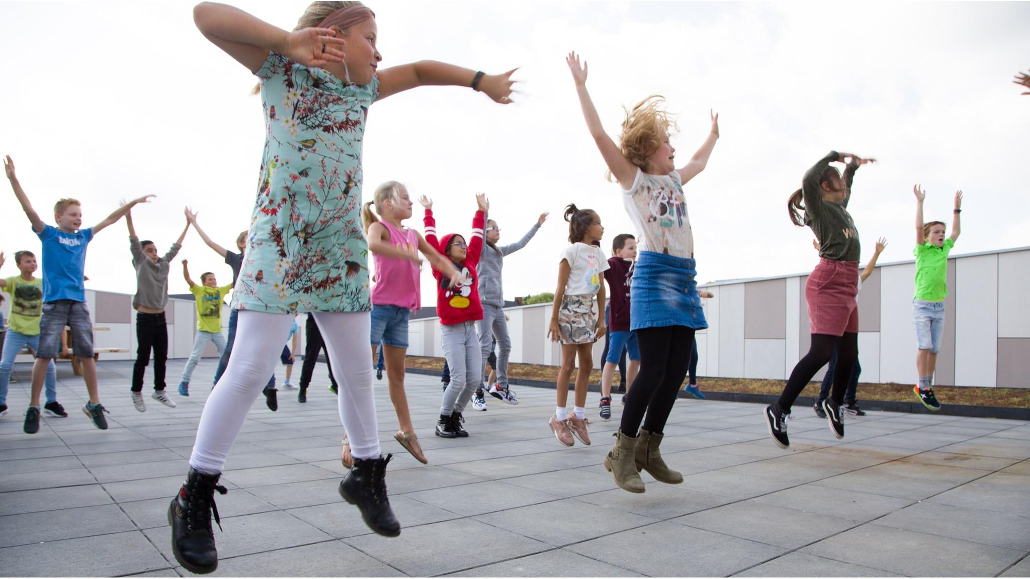 Kindcentrum De Uitdaging in Nijmegen, kinderen springen enthousiast op het schoolplein. Kindcentrum De Uitdaging in Nijmegen, kinderen springen enthousiast op het schoolplein.