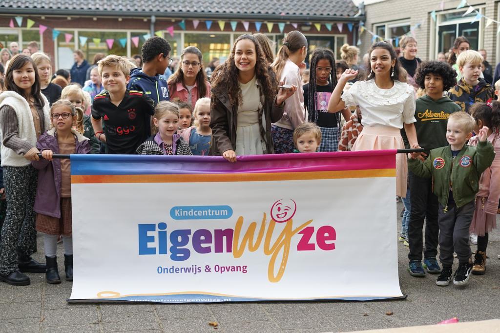 Kindcentrum Eigenwijze in Heemskerk viert een evenement met kinderen die een banner vasthouden.