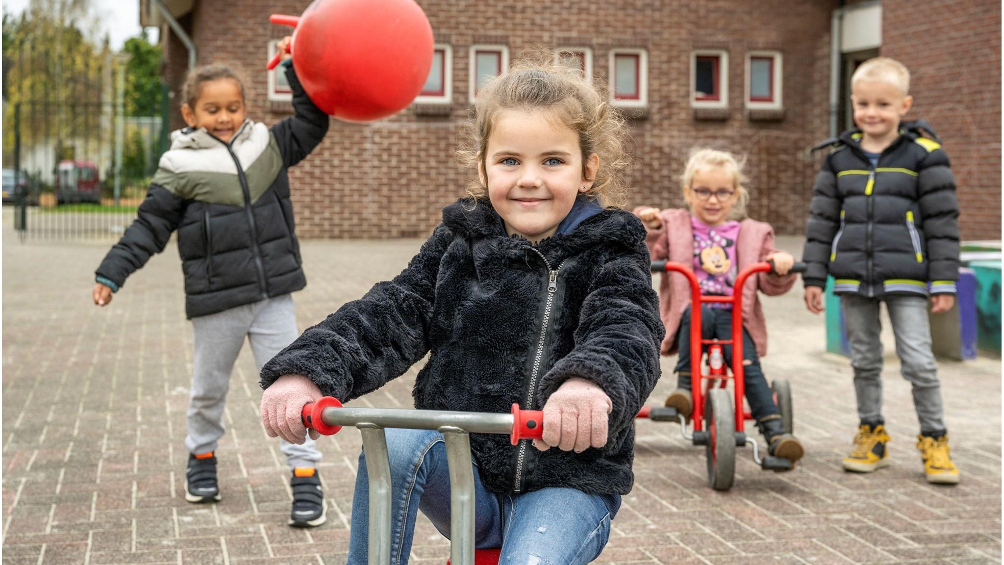 Kindcentrum Eikerwijs in Kessel, kinderen spelen met fietsen op het schoolplein.