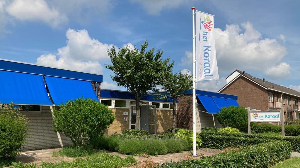 Kindcentrum het Koraal in Hoogeveen met blauwe luifels en een vlag in de voortuin. Kindcentrum het Koraal in Hoogeveen met blauwe luifels en een vlag in de voortuin.