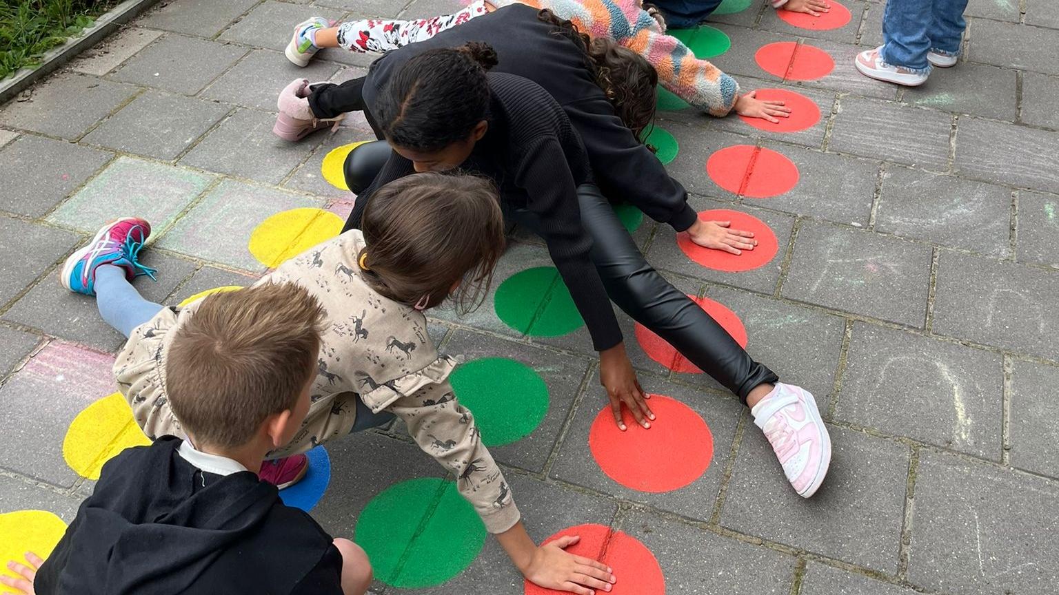 Kindcentrum Manjefiek in Maastricht, kinderen spelen op het schoolplein met kleurige stippen. Kindcentrum Manjefiek in Maastricht, kinderen spelen op het schoolplein met kleurige stippen.