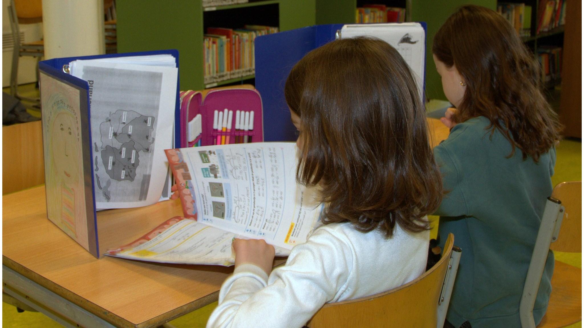Kinderen aan het werk achter hun bureau in de bibliotheek van basisschool Atlantis in Amsterdam.