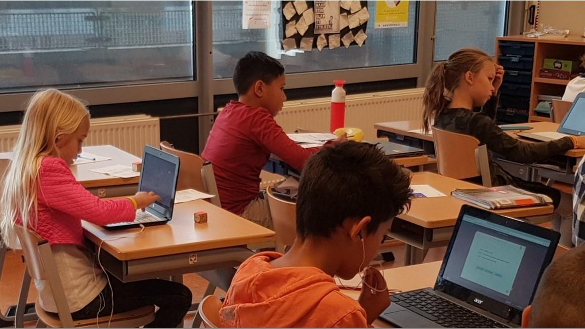 Kinderen aan het werk met laptops in een klaslokaal van basisschool De Brug in Aalsmeer.
