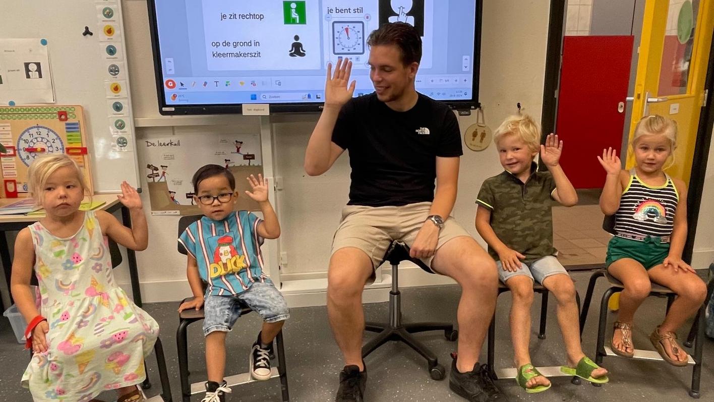 Kinderen en een docent van De Bargeweide in Eefde presenteren zich met hun handen omhoog in de klas. Kinderen en een docent van De Bargeweide in Eefde presenteren zich met hun handen omhoog in de klas.