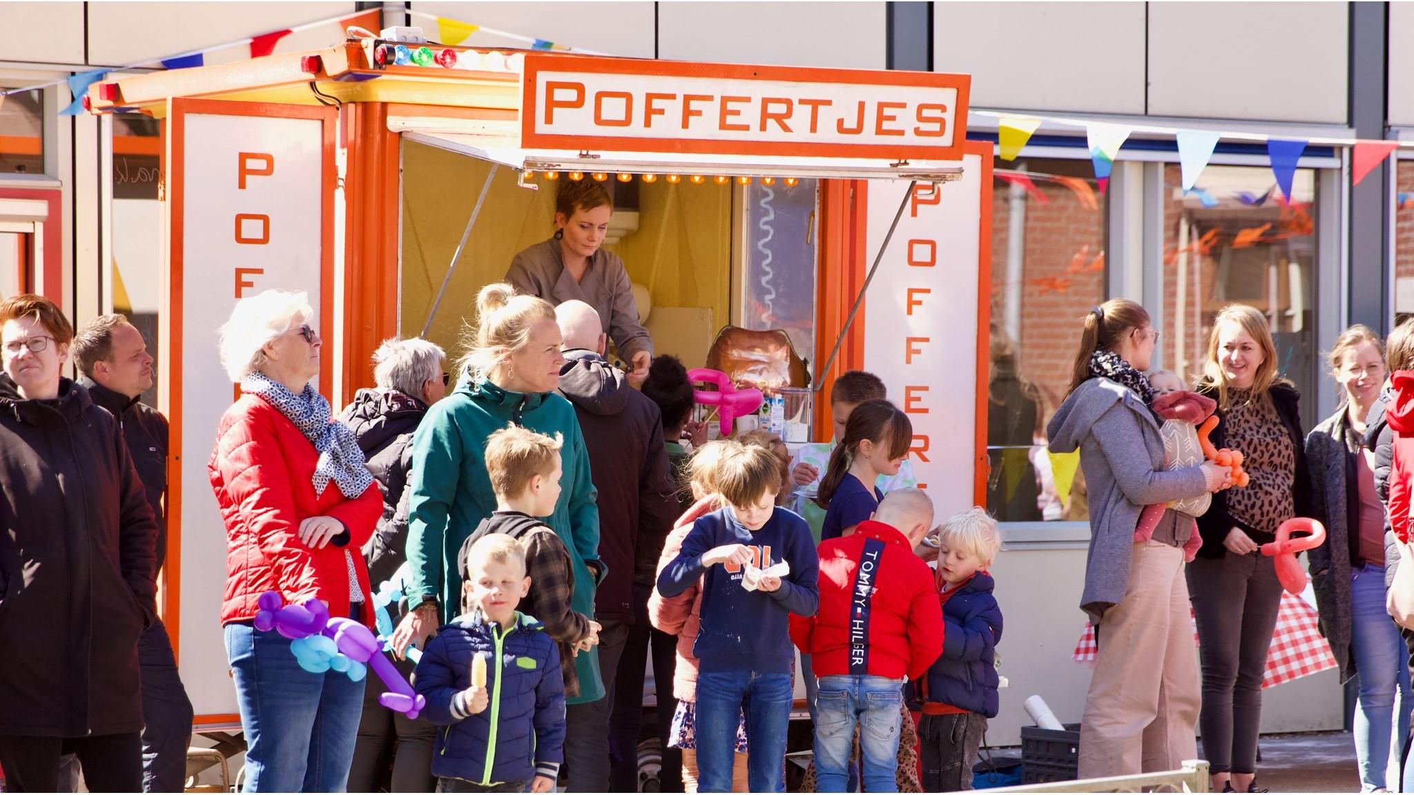 Kinderen en ouders genieten van poffertjes op het schoolplein van de Tjongerschool in Mildam.