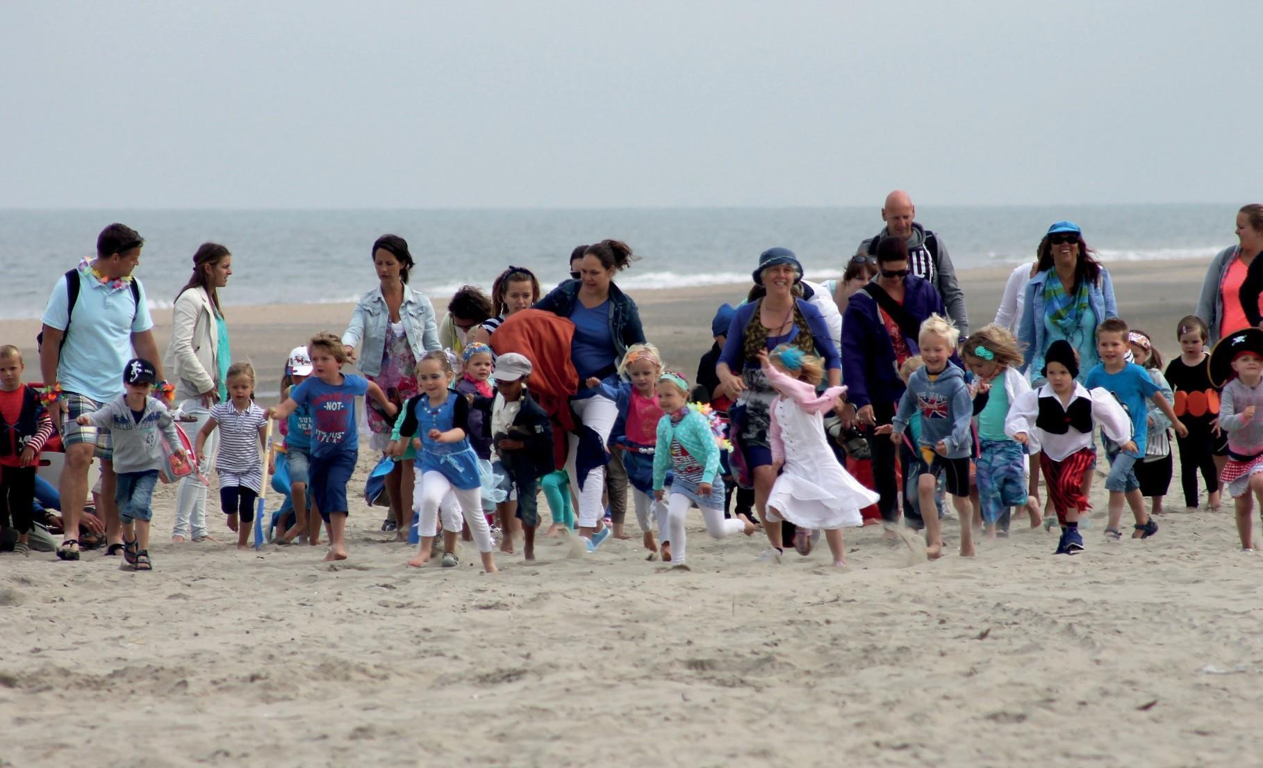 Kinderen en volwassenen rennen enthousiast over het strand tijdens een schooluitje van Jenaplanschool De Waterval in Lisse. Kinderen en volwassenen rennen enthousiast over het strand tijdens een schooluitje van Jenaplanschool De Waterval in Lisse.