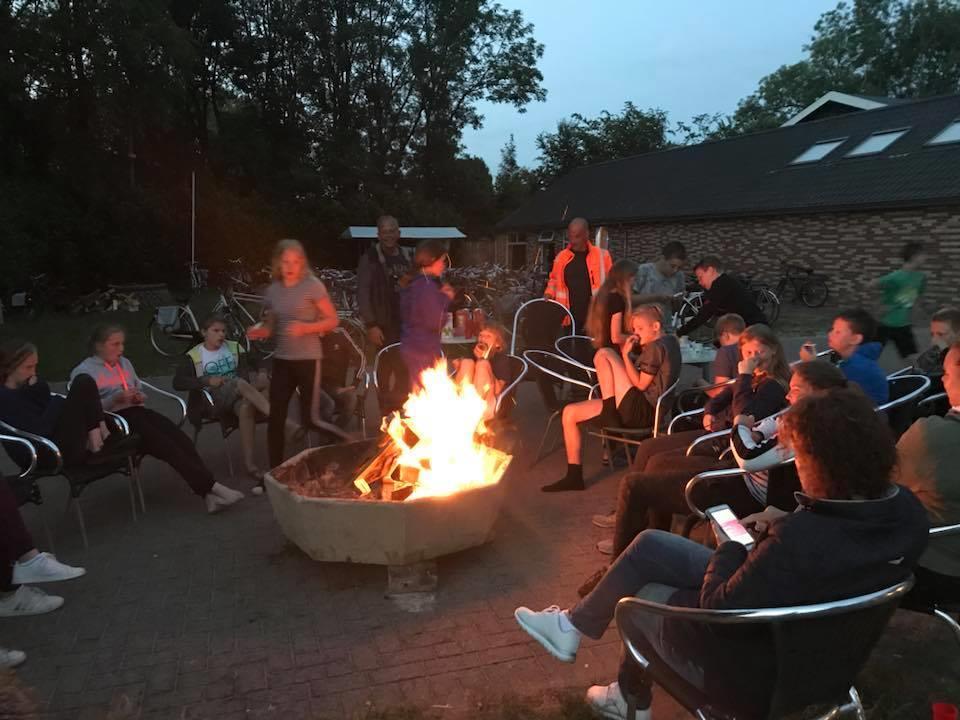 Kinderen en volwassenen van Dorpsschool Halle genieten van een gezellige avond rond een kampvuur op het schoolplein. Kinderen en volwassenen van Dorpsschool Halle genieten van een gezellige avond rond een kampvuur op het schoolplein.