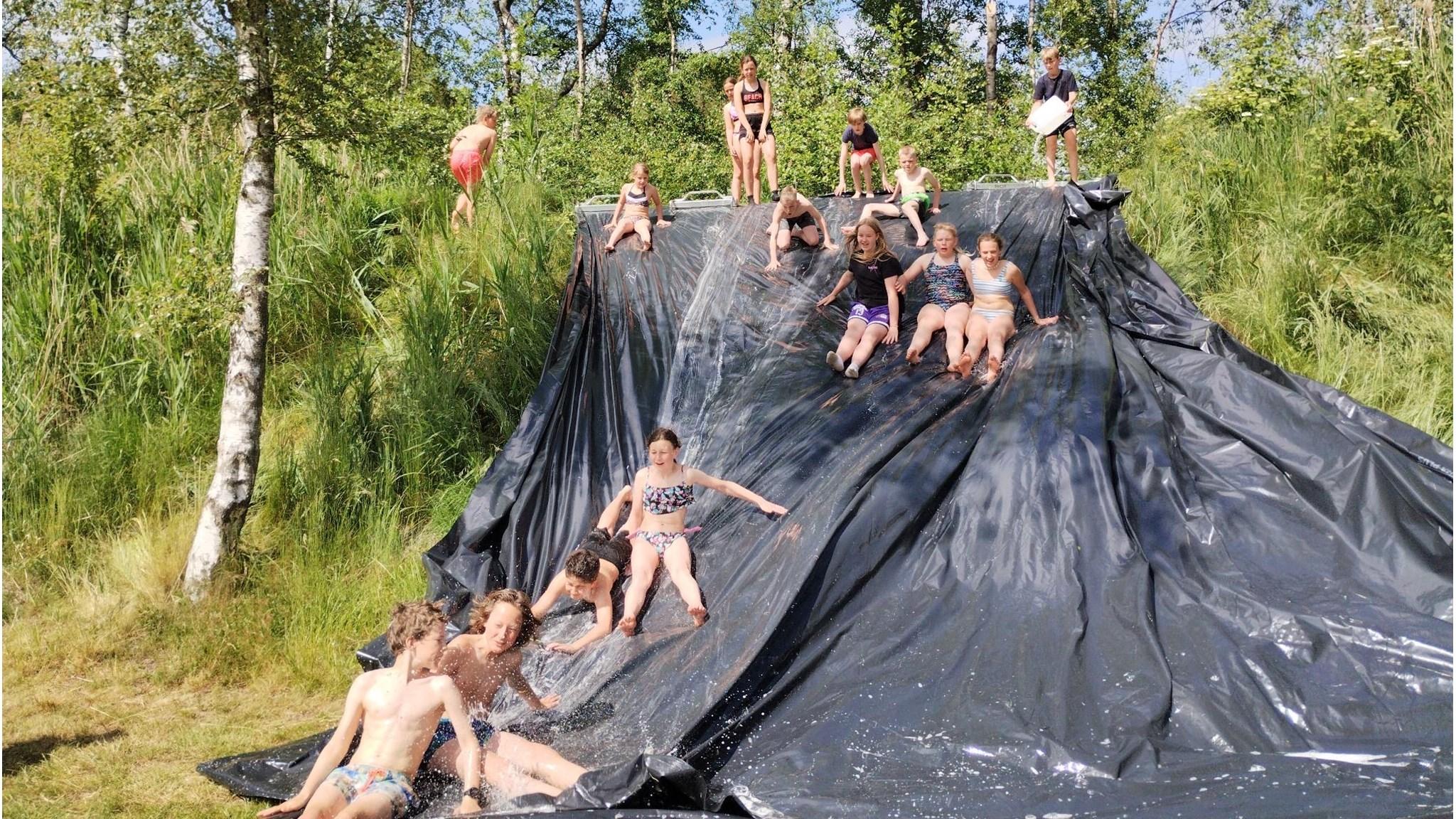 Kinderen genieten van een waterglijbaan op het schoolplein van Openbare Basisschool Kromme Akkers in Garnwerd. Kinderen genieten van een waterglijbaan op het schoolplein van Openbare Basisschool Kromme Akkers in Garnwerd.