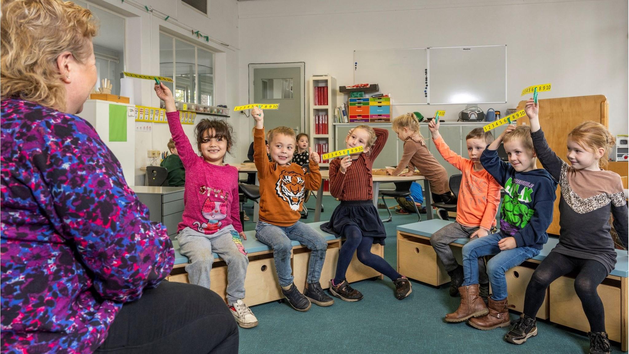 Kinderen in de klas van Basisschool De Kemp in Egchel steken hun handen op met cijferplaten tijdens een les. Kinderen in de klas van Basisschool De Kemp in Egchel steken hun handen op met cijferplaten tijdens een les.