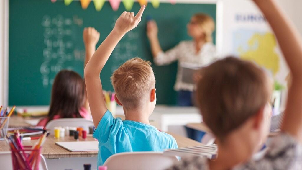 Kinderen in de klas van school 'Blink' in Culemborg steken hun handen op om deel te nemen aan de les. Kinderen in de klas van school 'Blink' in Culemborg steken hun handen op om deel te nemen aan de les.