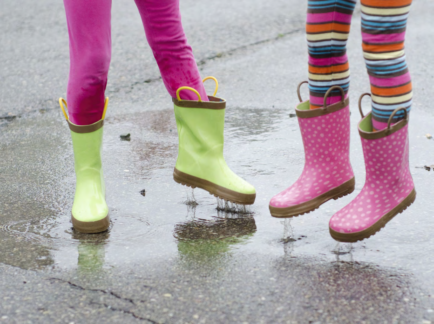 Kinderen in gekleurde regenlaarzen springen in plassen op het schoolplein van Basisschool Toermalijn in Wormerveer. Kinderen in gekleurde regenlaarzen springen in plassen op het schoolplein van Basisschool Toermalijn in Wormerveer.