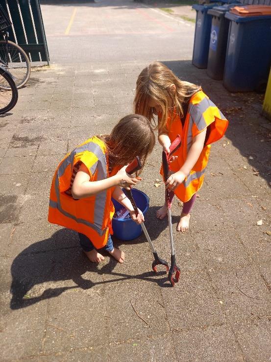 Kinderen in oranje veiligheidsvesten zijn aan het schoonmaken op het schoolplein van Openbare Basisschool Kiezel en Kei in Borculo. Kinderen in oranje veiligheidsvesten zijn aan het schoonmaken op het schoolplein van Openbare Basisschool Kiezel en Kei in Borculo.
