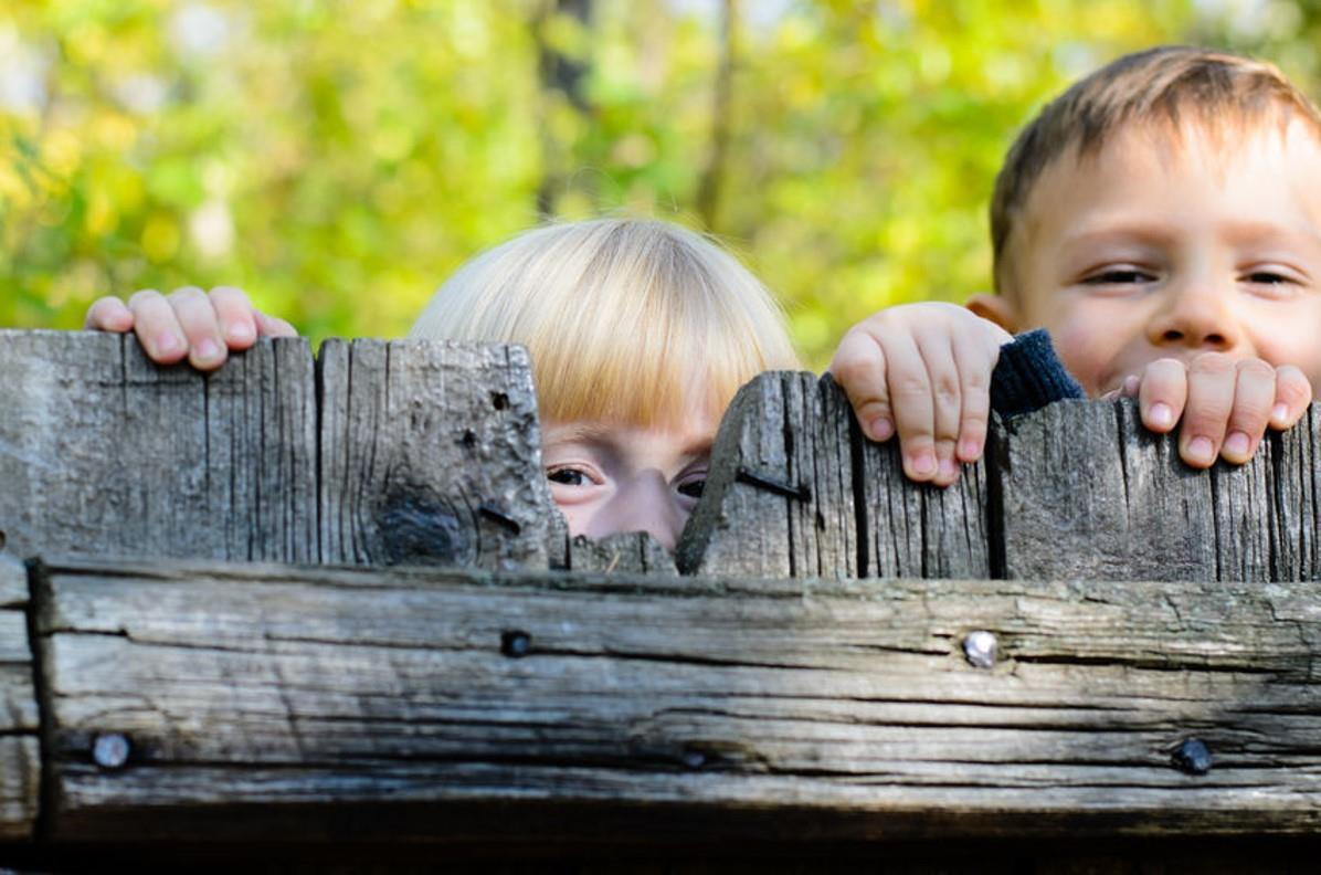 Kinderen kijken spelend over een houten omheining op het schoolplein van obs De Bosrand in Oostvoorne. Kinderen kijken spelend over een houten omheining op het schoolplein van obs De Bosrand in Oostvoorne.