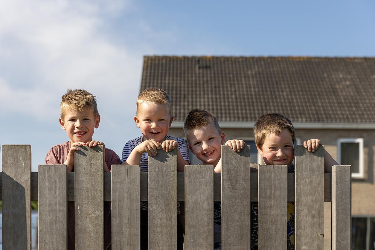 Kinderen lachen en leunen op een houten hek in de tuin van obs De Dennenkamp in Ommen. Kinderen lachen en leunen op een houten hek in de tuin van obs De Dennenkamp in Ommen.