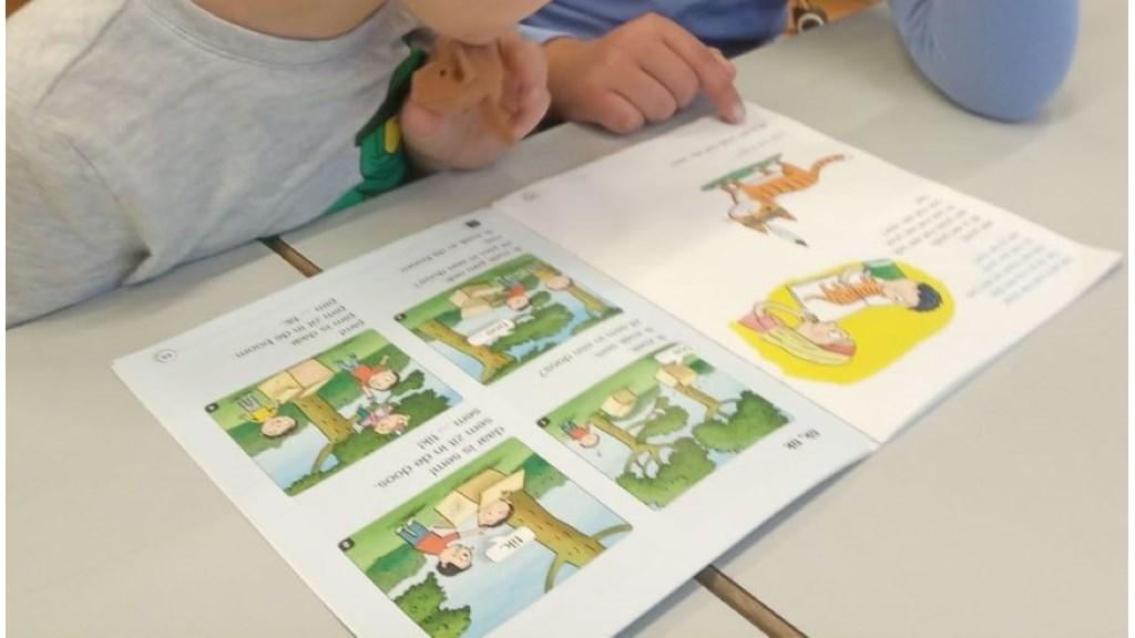 Kinderen lezen samen in een boek op De Meander in Lelystad.