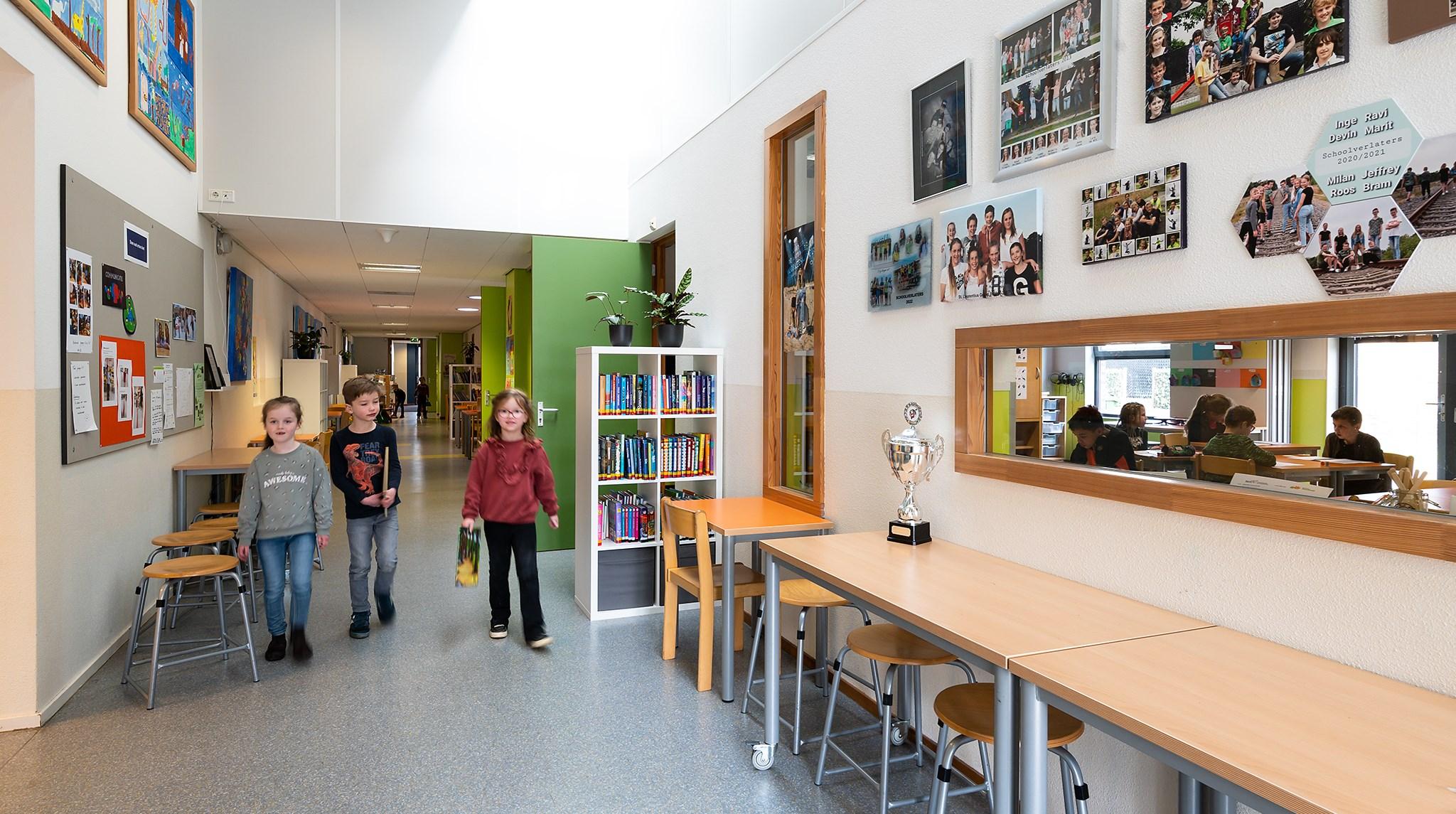 Kinderen lopen door de gang van Basisschool Swartbroek in Weert, omringd door kleurrijke kunst en boeken. Kinderen lopen door de gang van Basisschool Swartbroek in Weert, omringd door kleurrijke kunst en boeken.