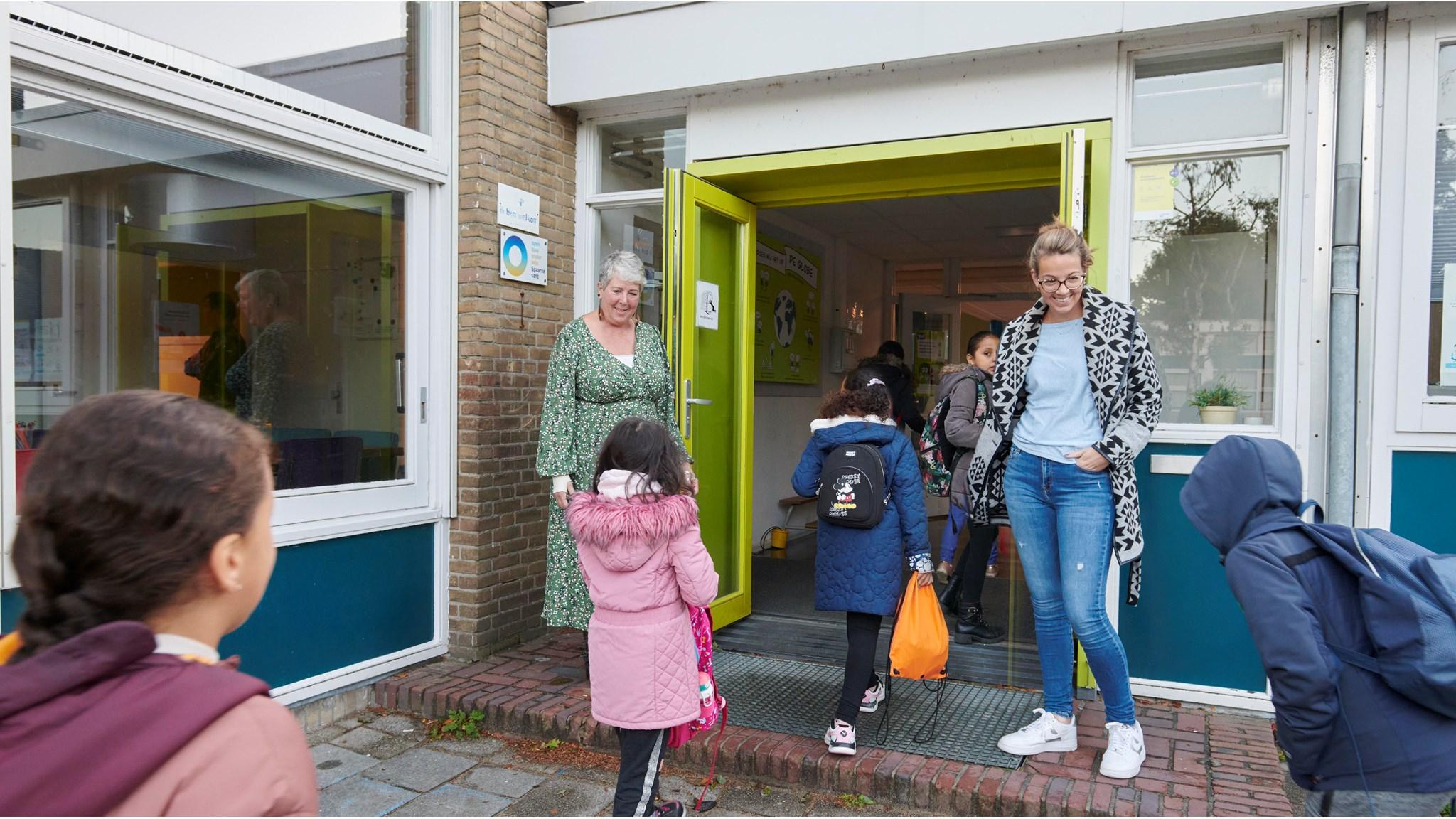 Kinderen lopen het schoolplein van OBS de Globe in Haarlem binnen onder begeleiding van medewerkers. Kinderen lopen het schoolplein van OBS de Globe in Haarlem binnen onder begeleiding van medewerkers.