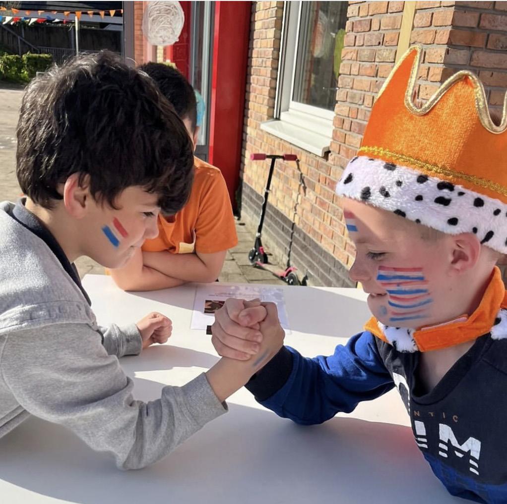 Kinderen met geschminkte gezichten strijden in een armworstelwedstrijd op het schoolplein van OBS Het Anker in Wijk bij Duurstede.