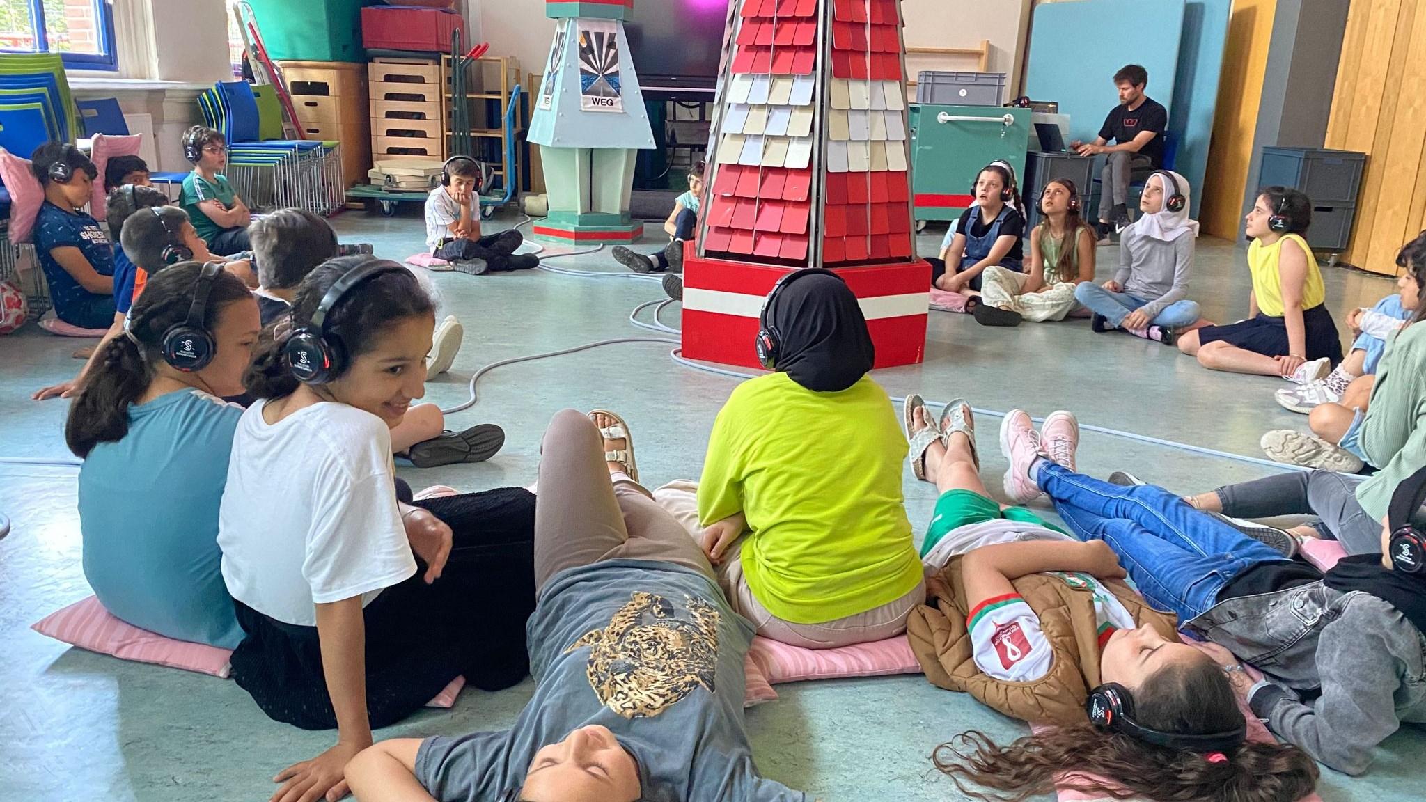 Kinderen met hoofdtelefoons luisteren in de klas van Al Ummah in Enschede.