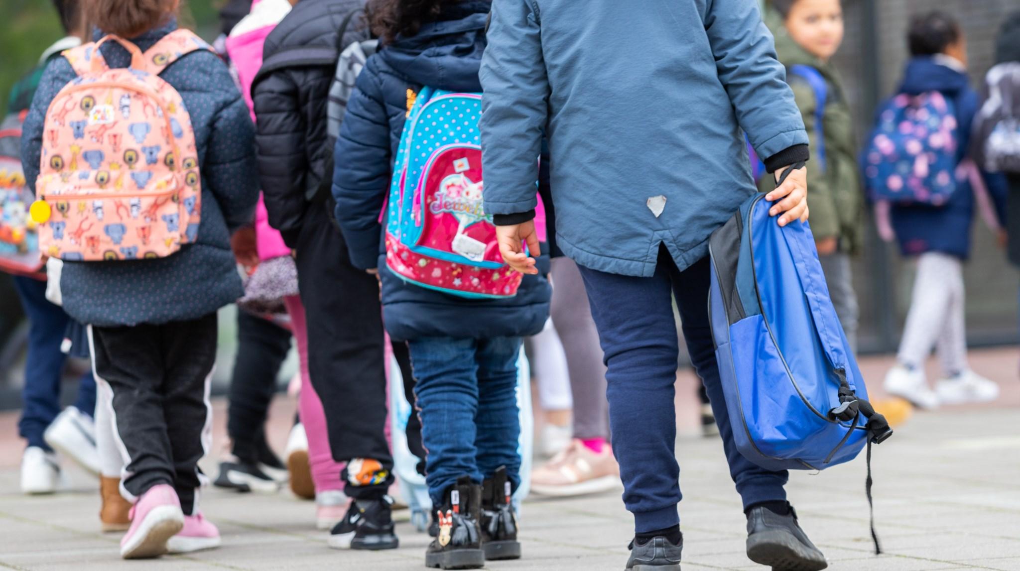 Kinderen met rugzakken lopen op het schoolplein van obs De Wijde Wereld in Amersfoort. Kinderen met rugzakken lopen op het schoolplein van obs De Wijde Wereld in Amersfoort.