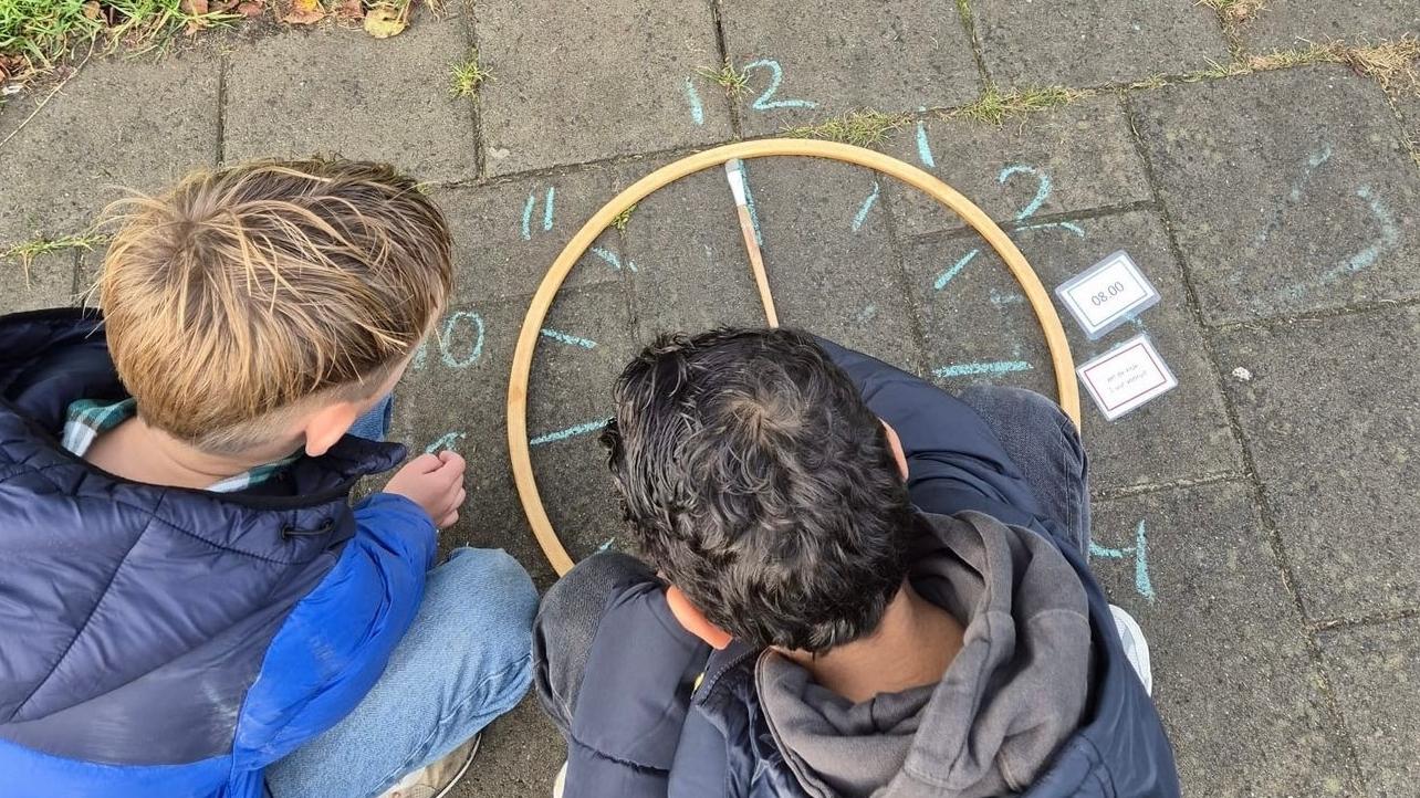Kinderen op het schoolplein van Parkwijck, Openbare Basisschool in Dordrecht leren klokkijken met een zelfgemaakt uurwerk. Kinderen op het schoolplein van Parkwijck, Openbare Basisschool in Dordrecht leren klokkijken met een zelfgemaakt uurwerk.