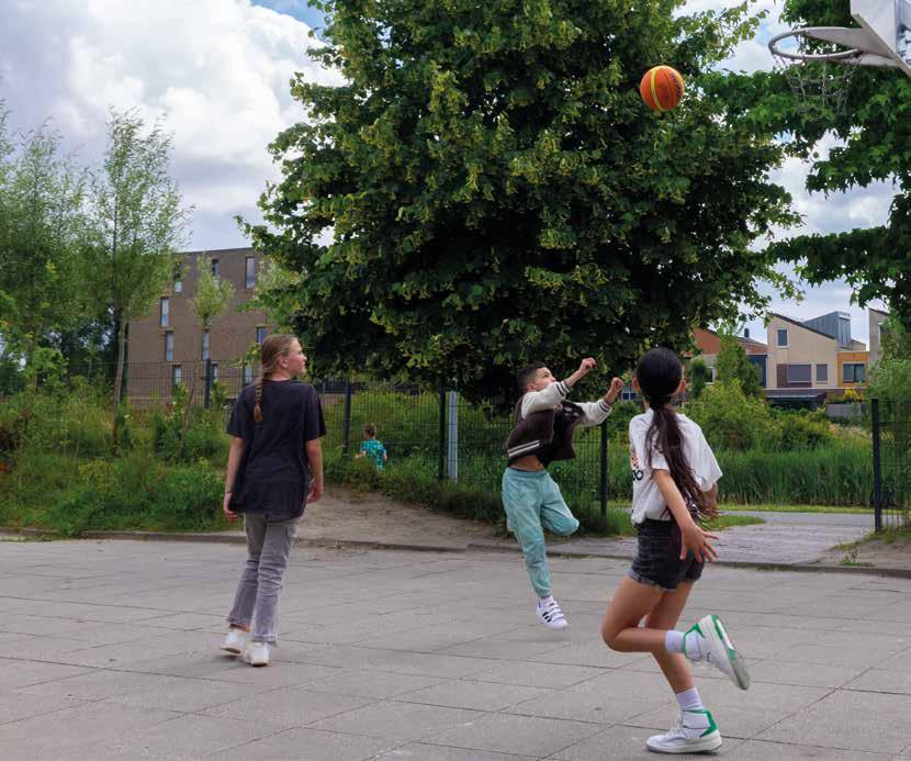 Kinderen spelen basketbal op het schoolplein van Obs De Optimist in Hoofddorp.