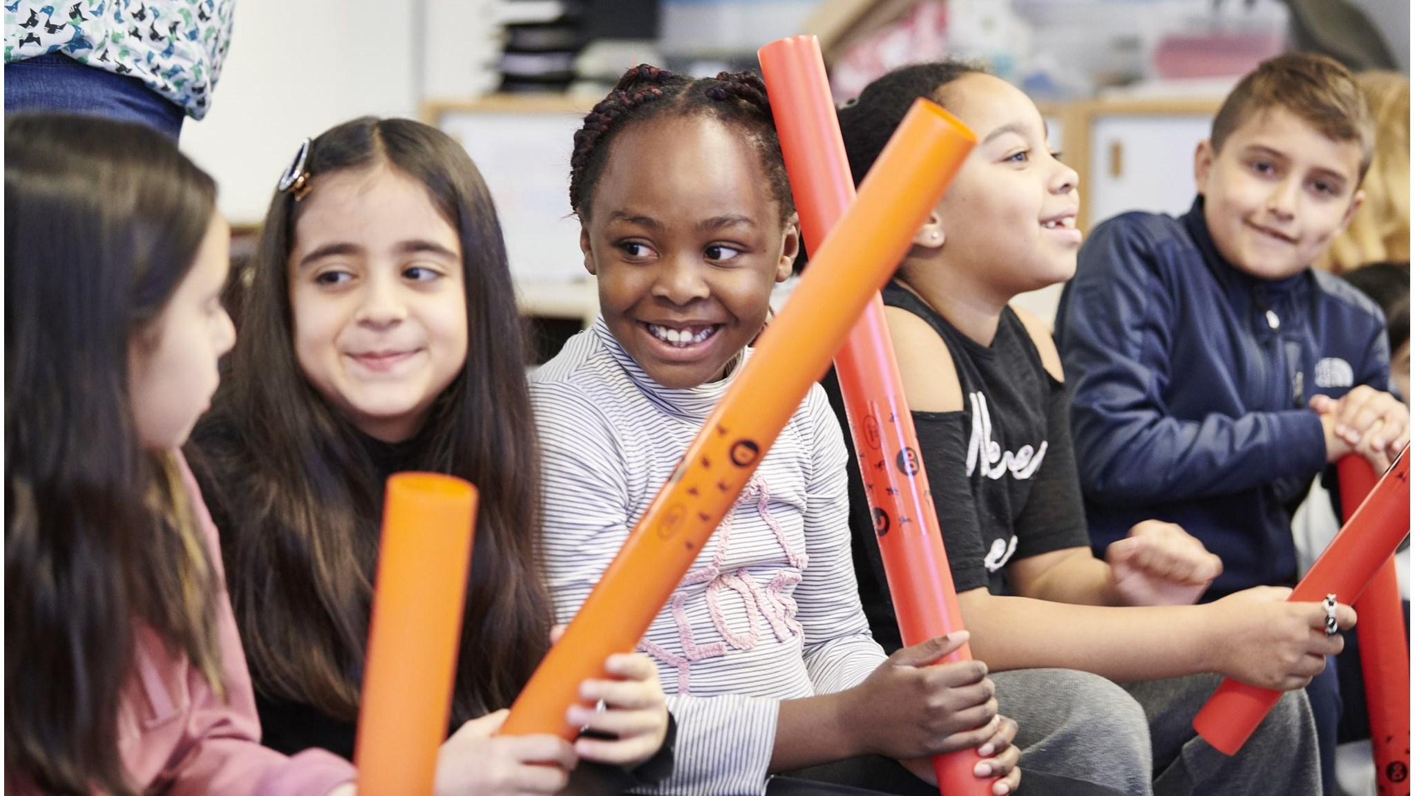 Kinderen spelen en lachen met oranje buizen in Basisschool Hubertus in Tilburg. Kinderen spelen en lachen met oranje buizen in Basisschool Hubertus in Tilburg.