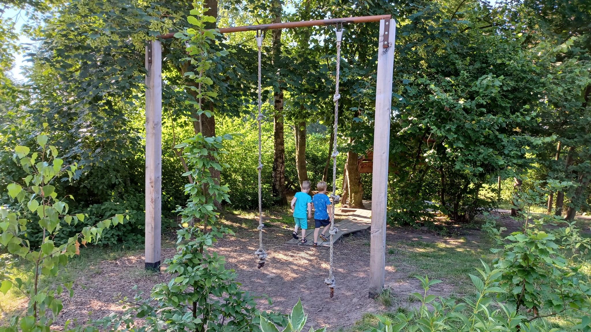 Kinderen spelen in de tuin van Basisschool Heeckeren in Goor, met schommels omringd door groen. Kinderen spelen in de tuin van Basisschool Heeckeren in Goor, met schommels omringd door groen.