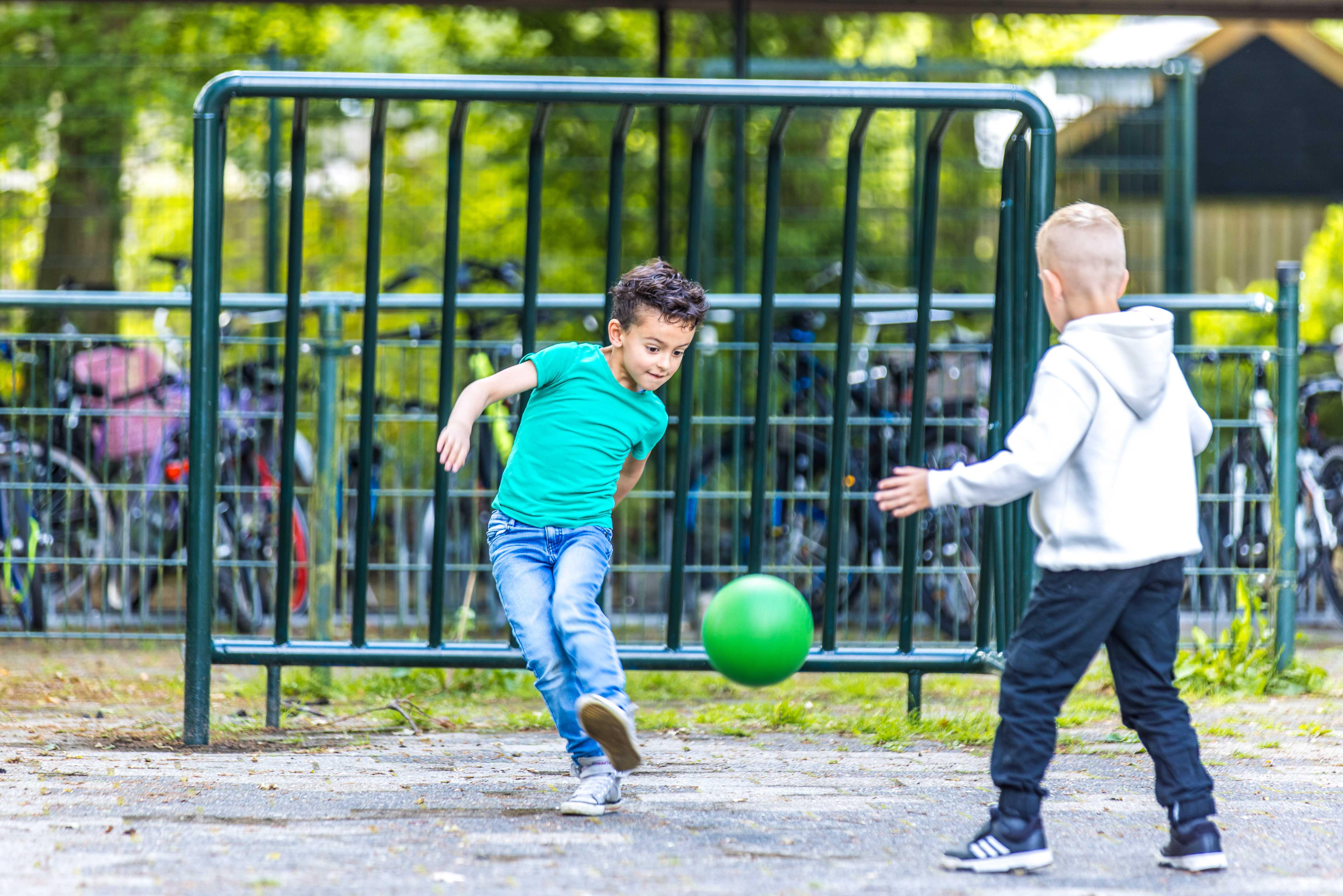 Kinderen spelen met een groene bal op het schoolplein van CBS De Parel in Roden. Kinderen spelen met een groene bal op het schoolplein van CBS De Parel in Roden.
