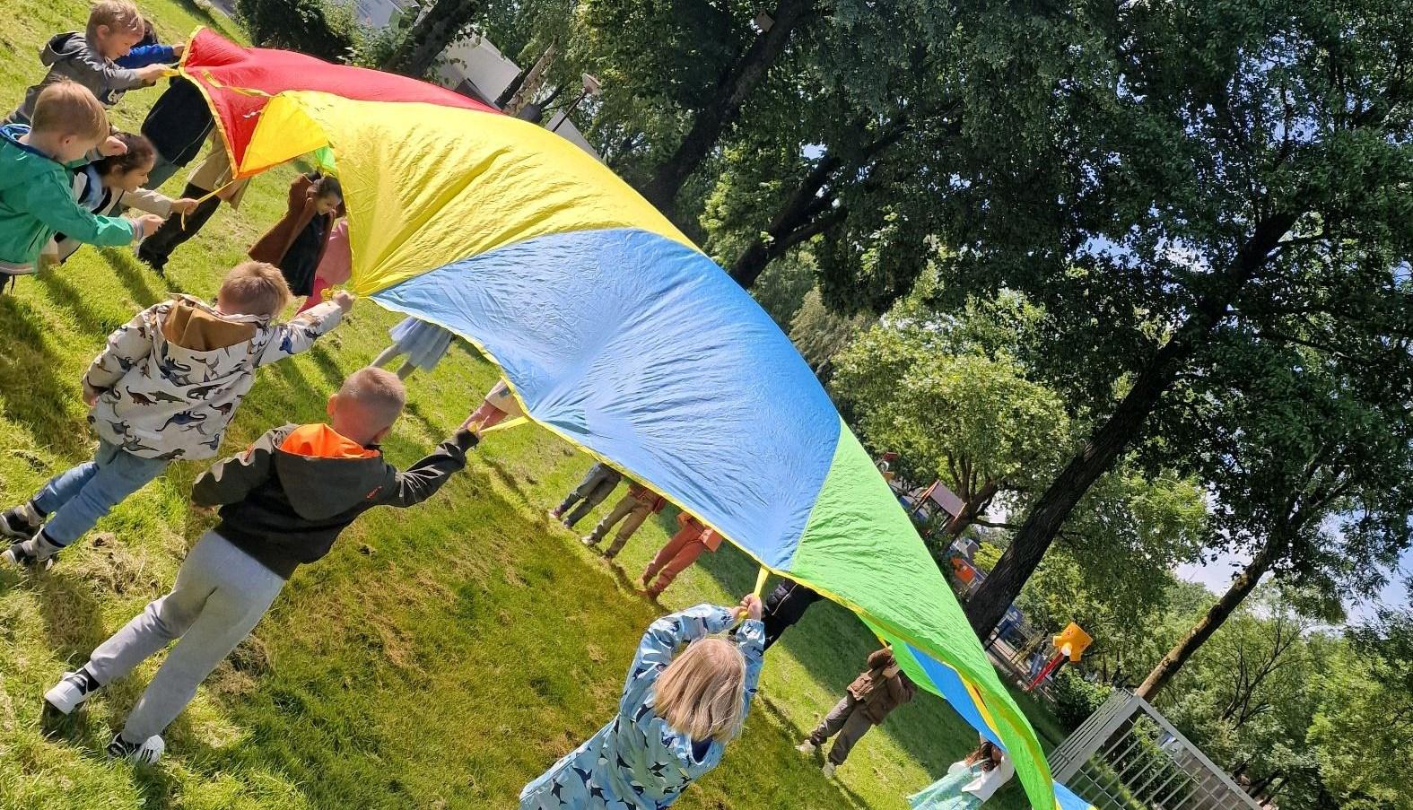 Kinderen spelen met een kleurige parachute op het schoolplein van De Meander in Nieuwegein.