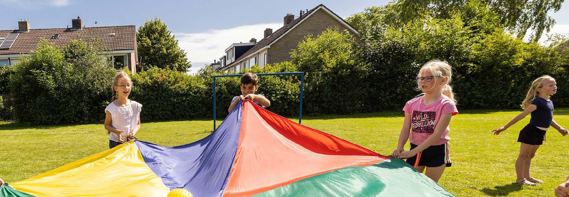 Kinderen spelen met een kleurrijke parachute op het schoolplein van Christelijke Basisschool de Roerganger in Heerenveen. Kinderen spelen met een kleurrijke parachute op het schoolplein van Christelijke Basisschool de Roerganger in Heerenveen.