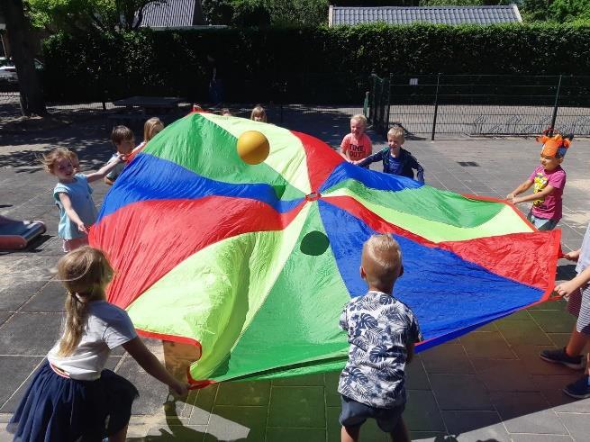 Kinderen spelen met een kleurrijke parachute op het schoolplein van de Rooms Katholieke Basisschool Sint Martinus in Voorst. Kinderen spelen met een kleurrijke parachute op het schoolplein van de Rooms Katholieke Basisschool Sint Martinus in Voorst.