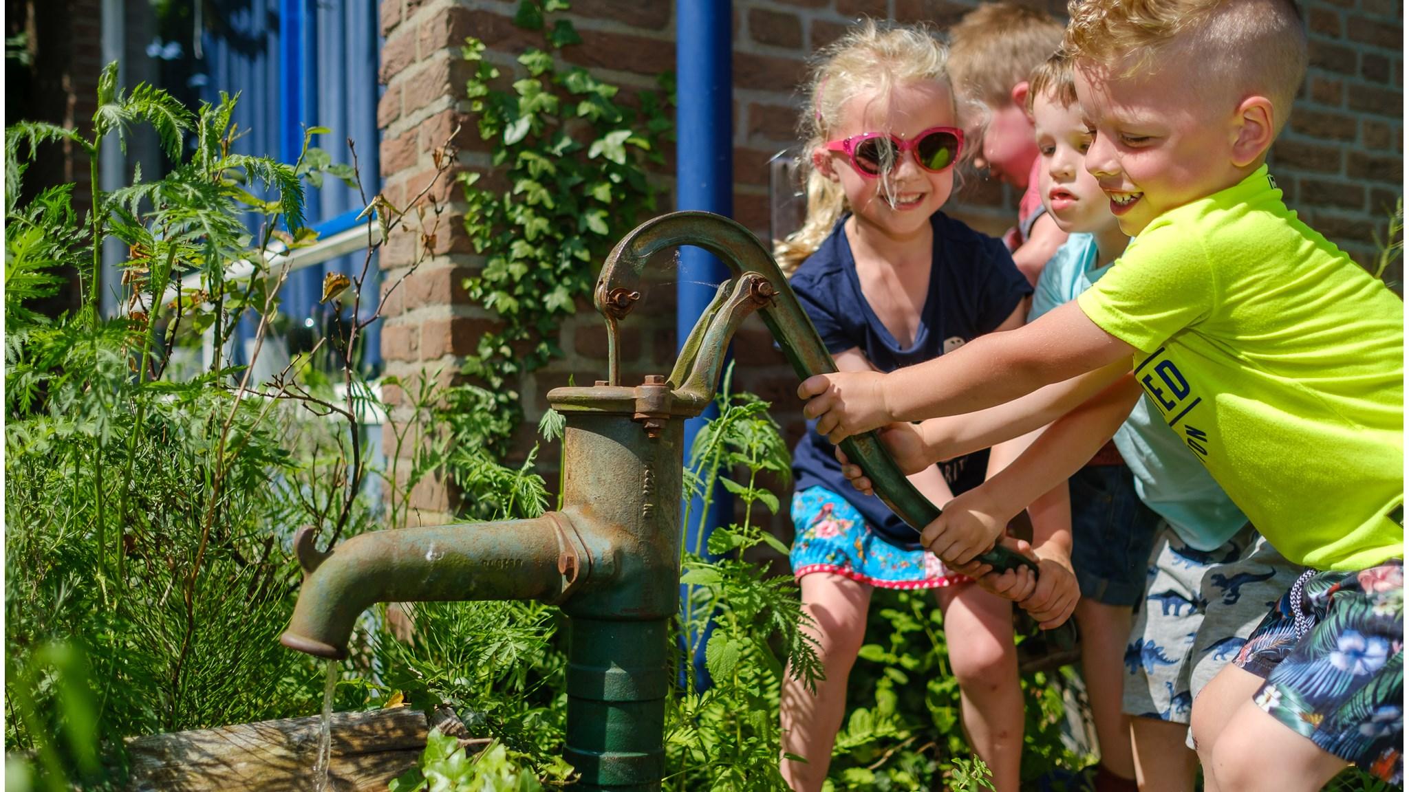 Kinderen spelen met een oude pomp op het schoolplein van PCBO Prinses Juliana in Lieren. Kinderen spelen met een oude pomp op het schoolplein van PCBO Prinses Juliana in Lieren.
