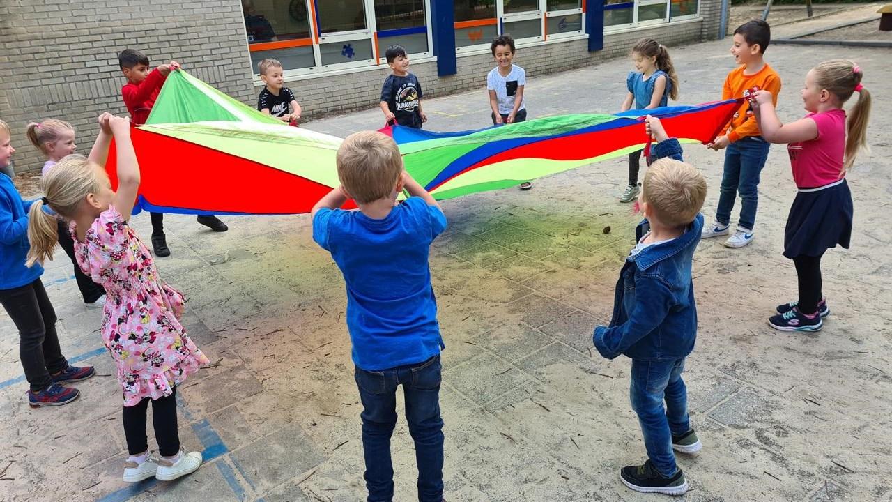 Kinderen spelen met een parachute op het schoolplein van obs Willem Wilmink in Enschede. Kinderen spelen met een parachute op het schoolplein van obs Willem Wilmink in Enschede.