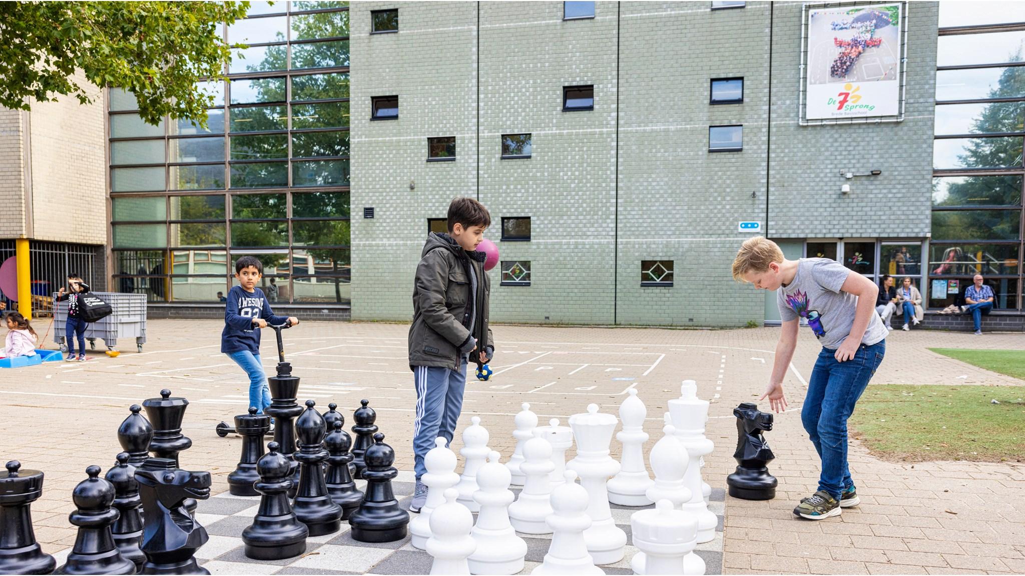 Kinderen spelen met grote schaakstukken op het schoolplein van Openbare Basisschool De Zevensprong in Almere. Kinderen spelen met grote schaakstukken op het schoolplein van Openbare Basisschool De Zevensprong in Almere.