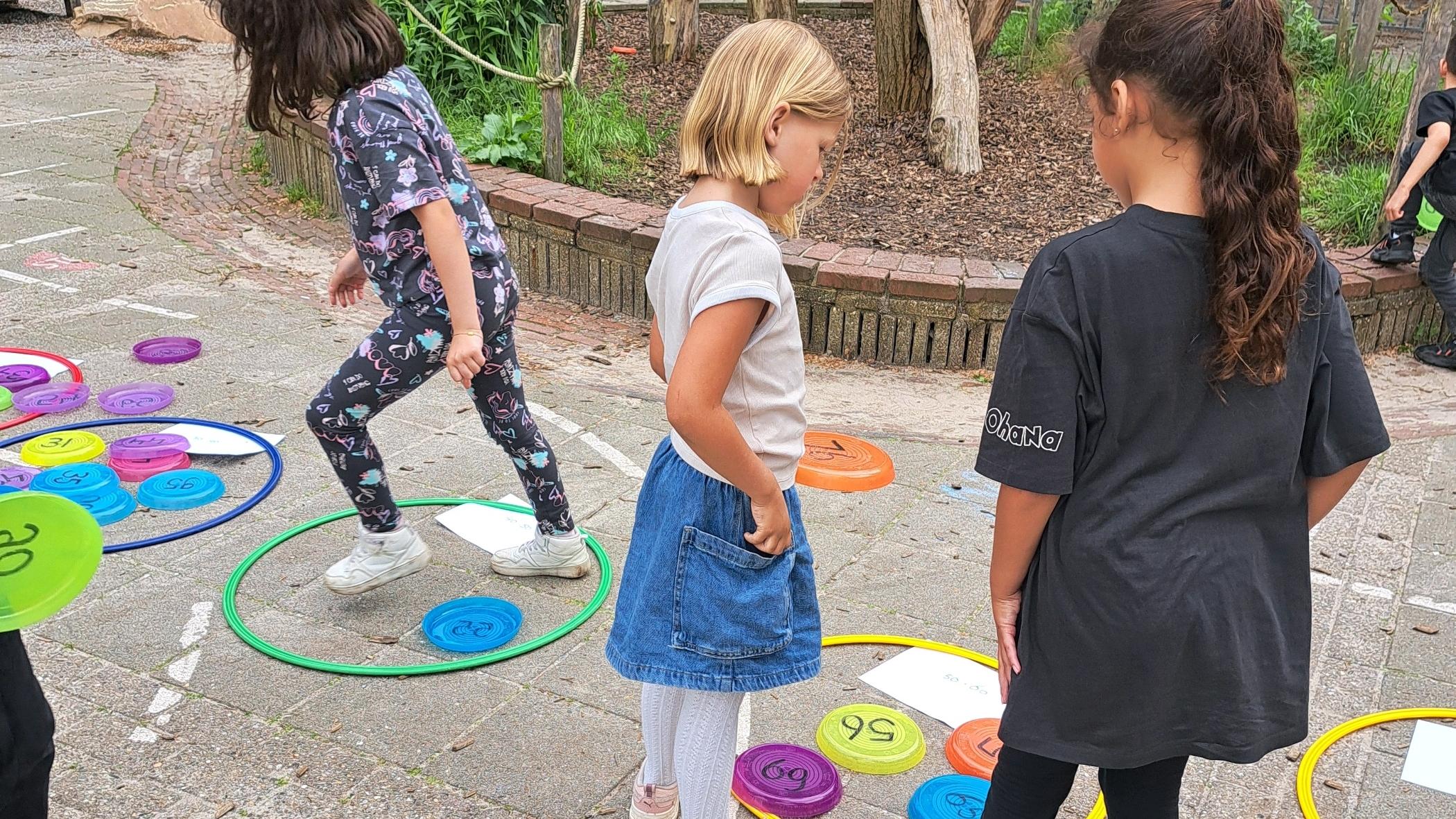 Kinderen spelen met kleurrijke rondjes op het schoolplein van KBS Kameleon in Amersfoort. Kinderen spelen met kleurrijke rondjes op het schoolplein van KBS Kameleon in Amersfoort.