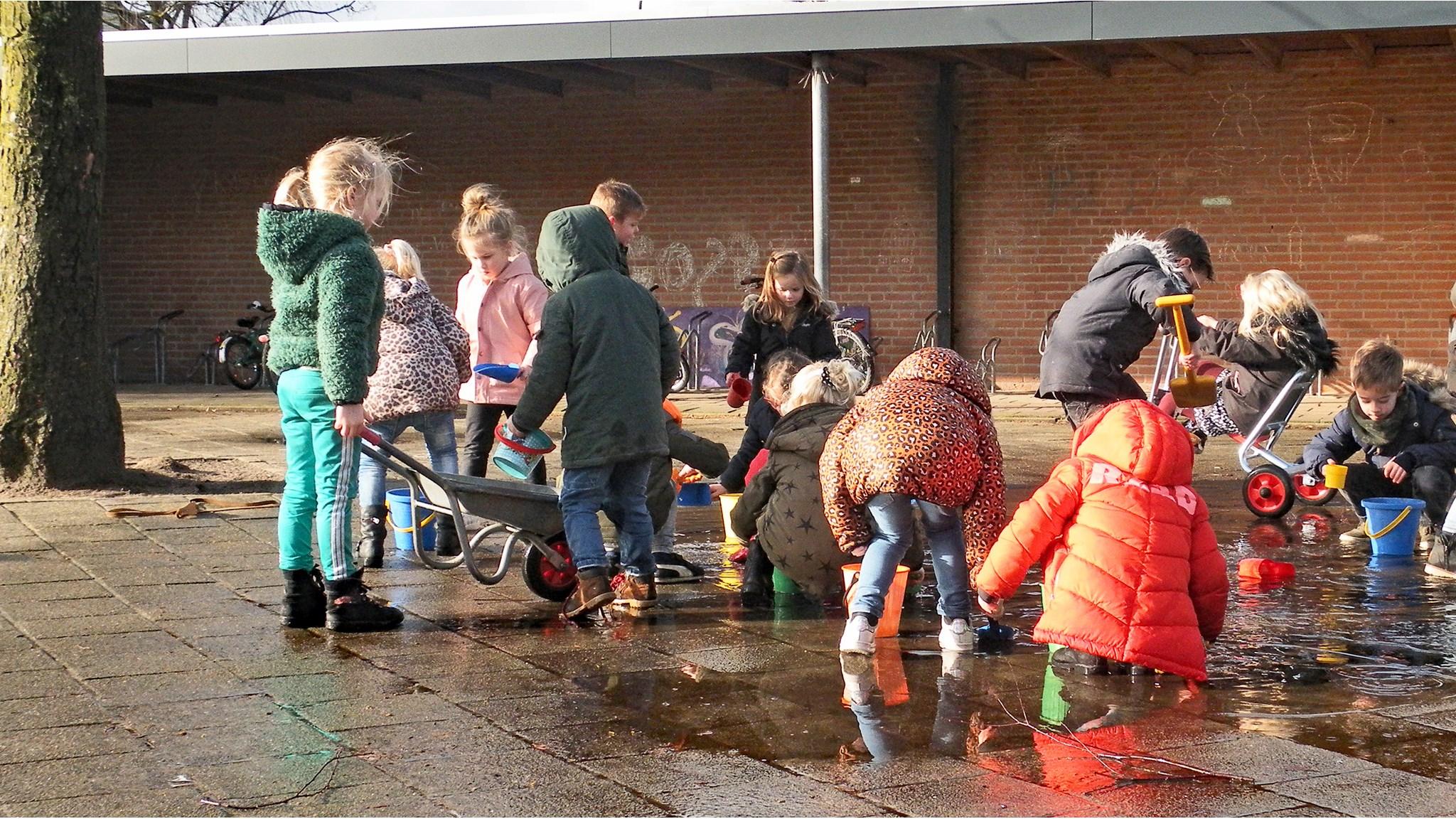 Kinderen spelen met water en speelgoed op het schoolplein van Basisschool De Empel in Erp. Kinderen spelen met water en speelgoed op het schoolplein van Basisschool De Empel in Erp.
