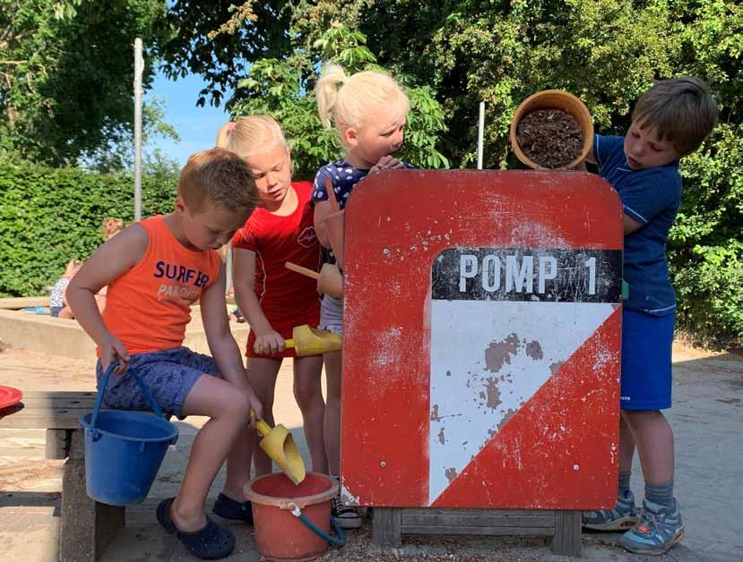 Kinderen spelen met water en zand bij de pompkorf op het schoolplein van OBS J.H. Isings in Empe. Kinderen spelen met water en zand bij de pompkorf op het schoolplein van OBS J.H. Isings in Empe.
