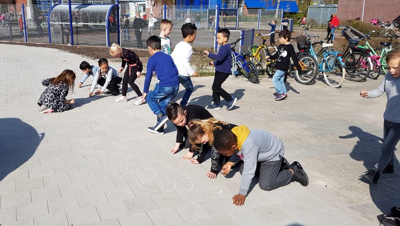 Kinderen spelen op het schoolplein van De Finnjol in Lelystad met krijt.