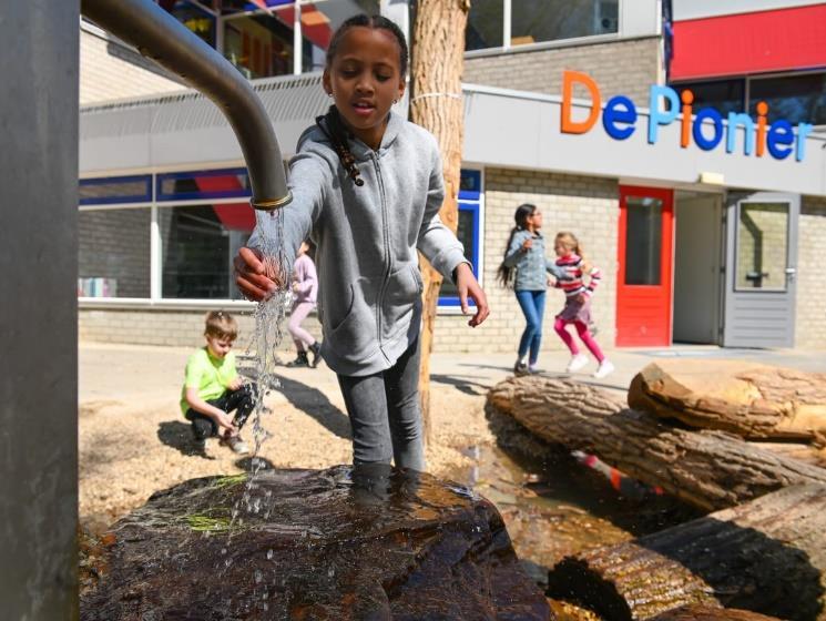 Kinderen spelen op het schoolplein van De Pionier in Rotterdam, terwijl een meisje water uit een kraan laat stromen. Kinderen spelen op het schoolplein van De Pionier in Rotterdam, terwijl een meisje water uit een kraan laat stromen.