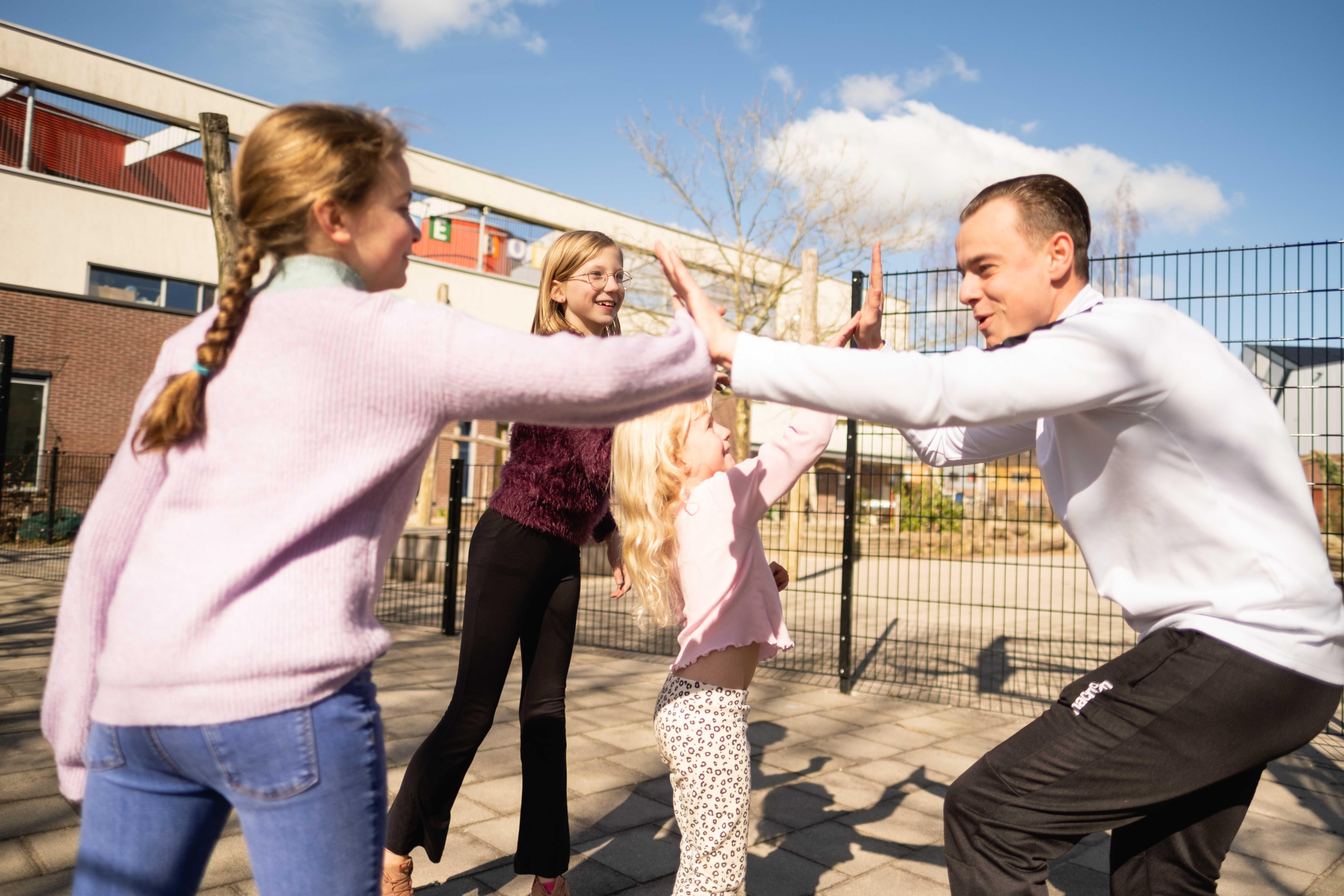 Kinderen spelen samen met een docent op het schoolplein van Montessori Basisschool De Kosmos in Hoogland. Kinderen spelen samen met een docent op het schoolplein van Montessori Basisschool De Kosmos in Hoogland.