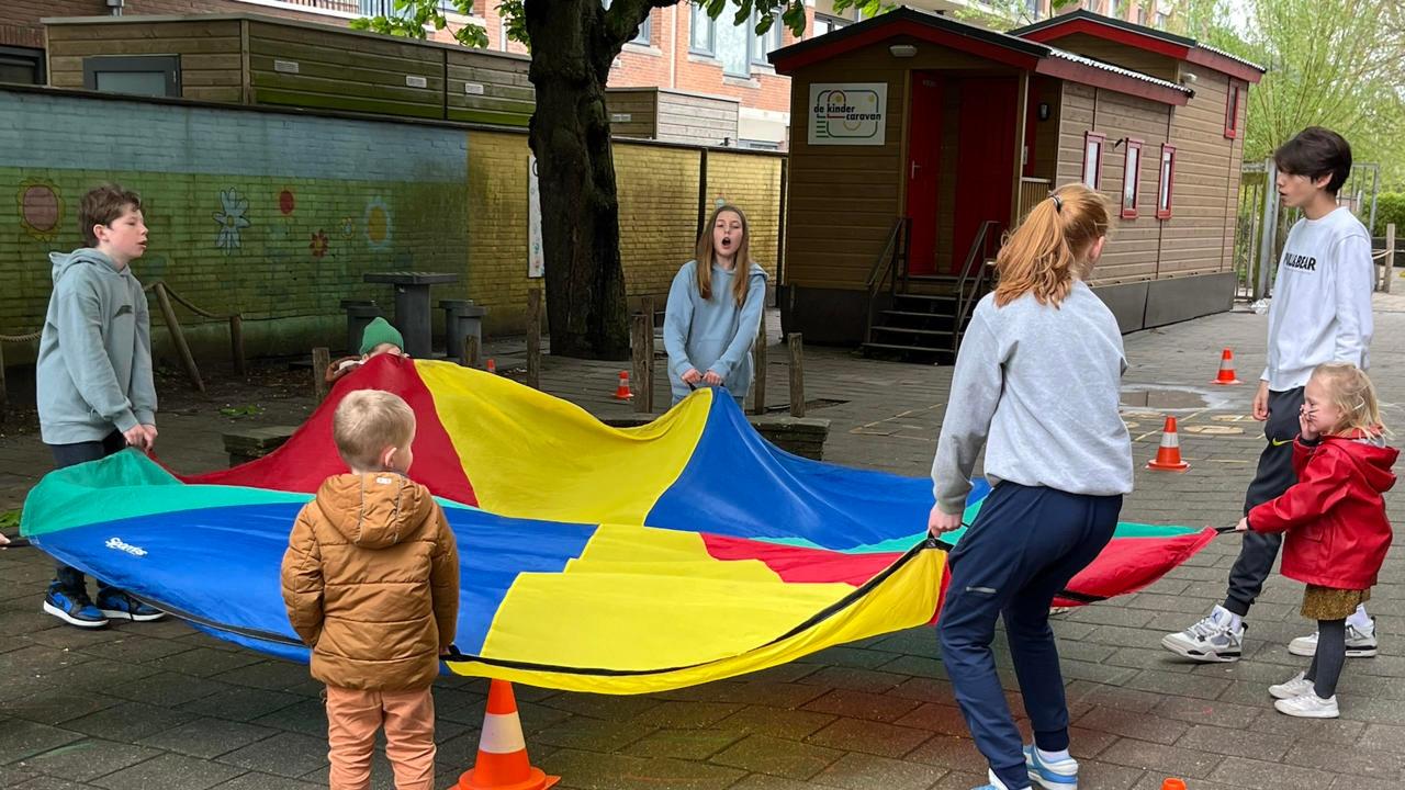Kinderen spelen samen met een parachute op het schoolplein van Liduina in Den Haag. Kinderen spelen samen met een parachute op het schoolplein van Liduina in Den Haag.