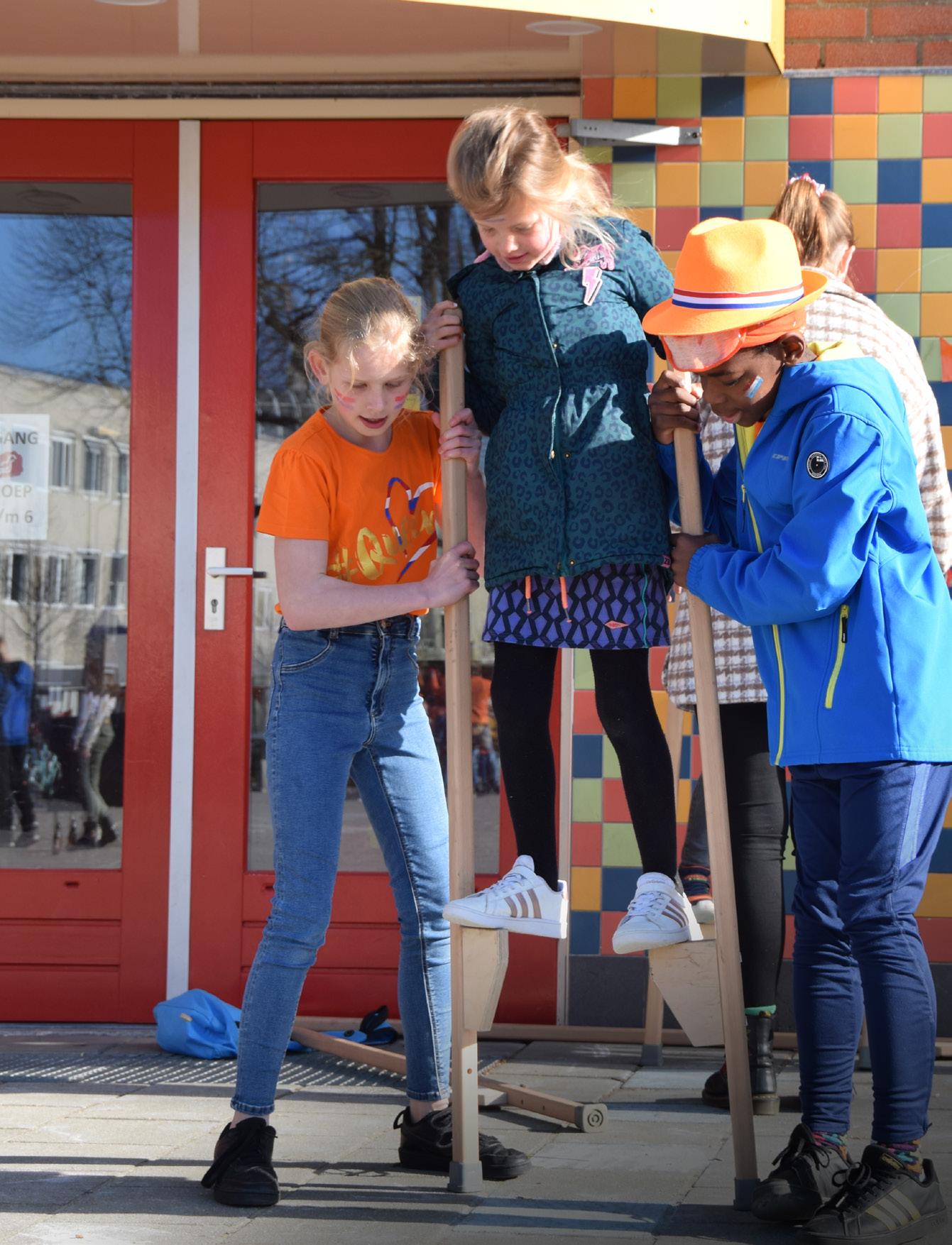 Kinderen spelen samen met stokken op het schoolplein van de Paasbergschool in Ede.
