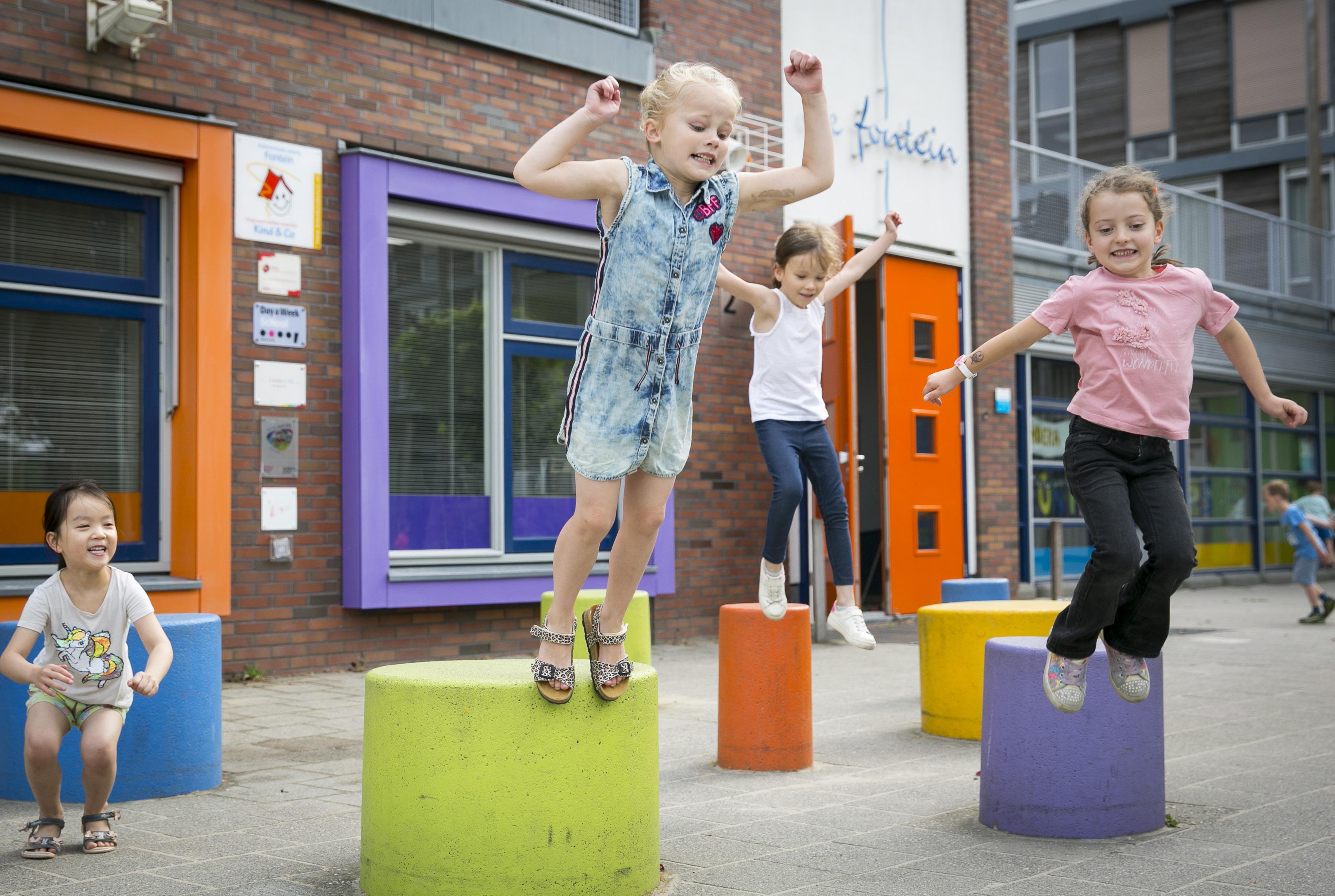 Kinderen springen vrolijk op de kleurrijke speelobjecten op het schoolplein van De Fontein Houten. Kinderen springen vrolijk op de kleurrijke speelobjecten op het schoolplein van De Fontein Houten.