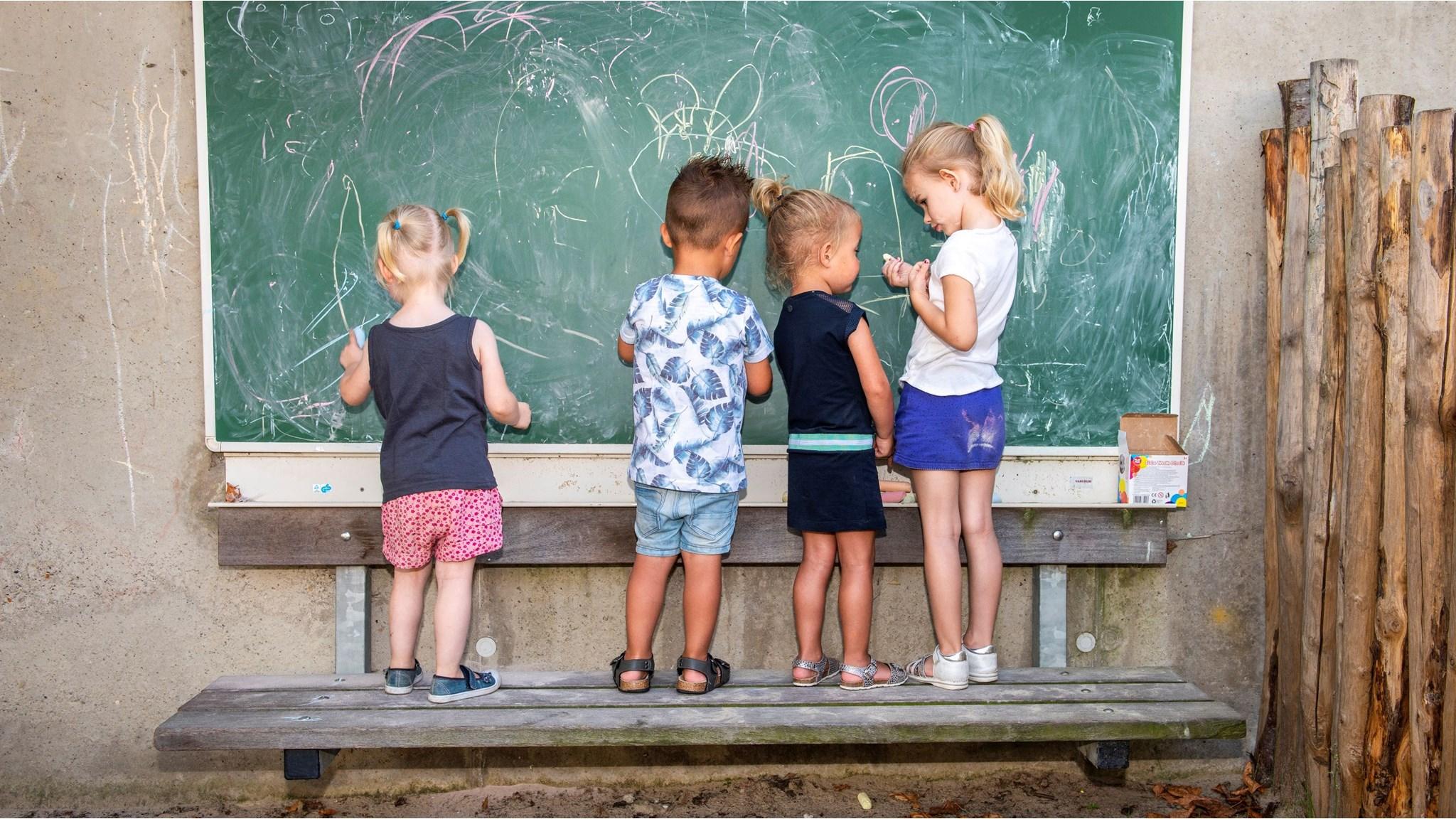 Kinderen tekenen met krijt op een schoolbord op het schoolplein van KC LEEF in Kessel. Kinderen tekenen met krijt op een schoolbord op het schoolplein van KC LEEF in Kessel.