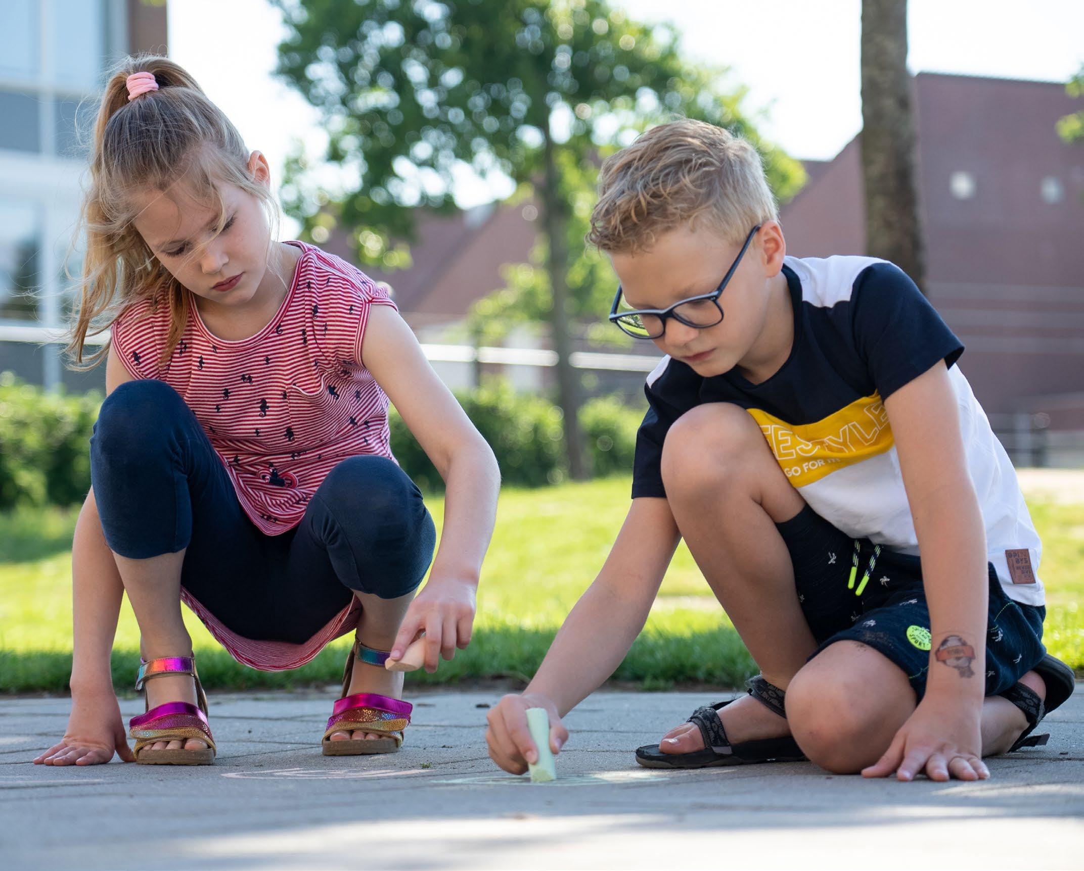 Kinderen tekenen met krijt op het schoolplein van de Hubertusschool in Herten. Kinderen tekenen met krijt op het schoolplein van de Hubertusschool in Herten.